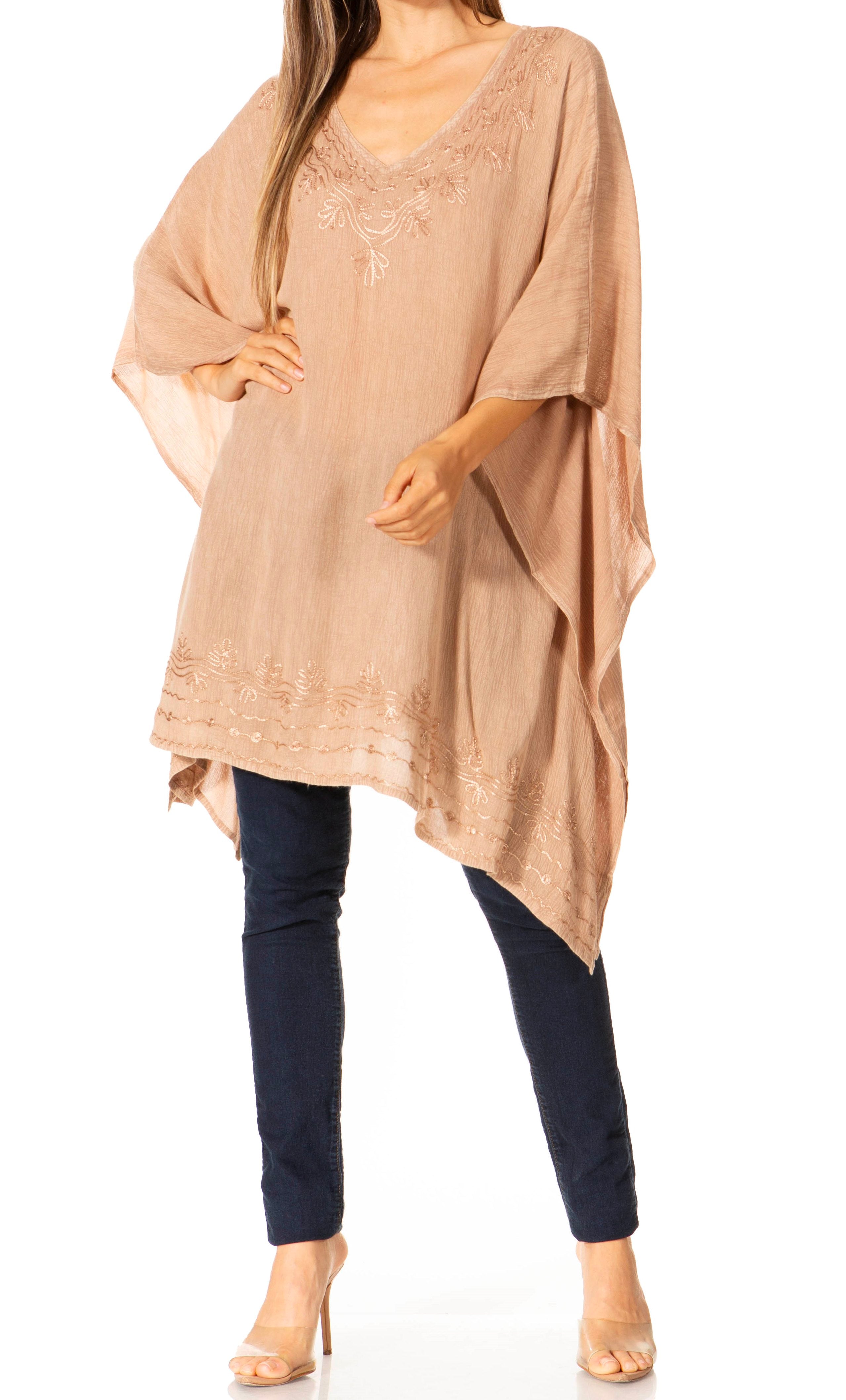 Woman wearing a beige poncho and navy pants on a white background