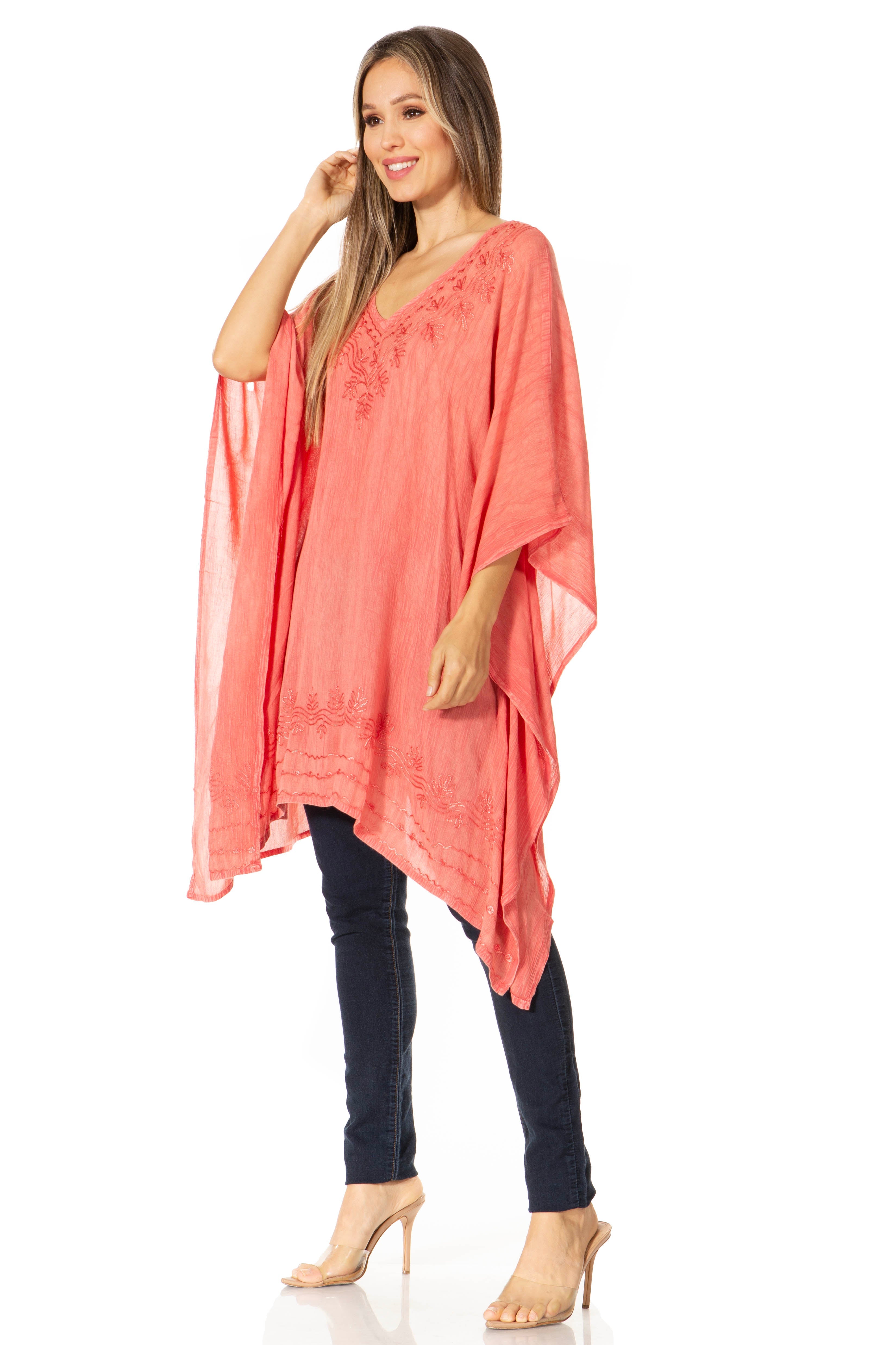Woman wearing a coral poncho over a black top and pants on a white background