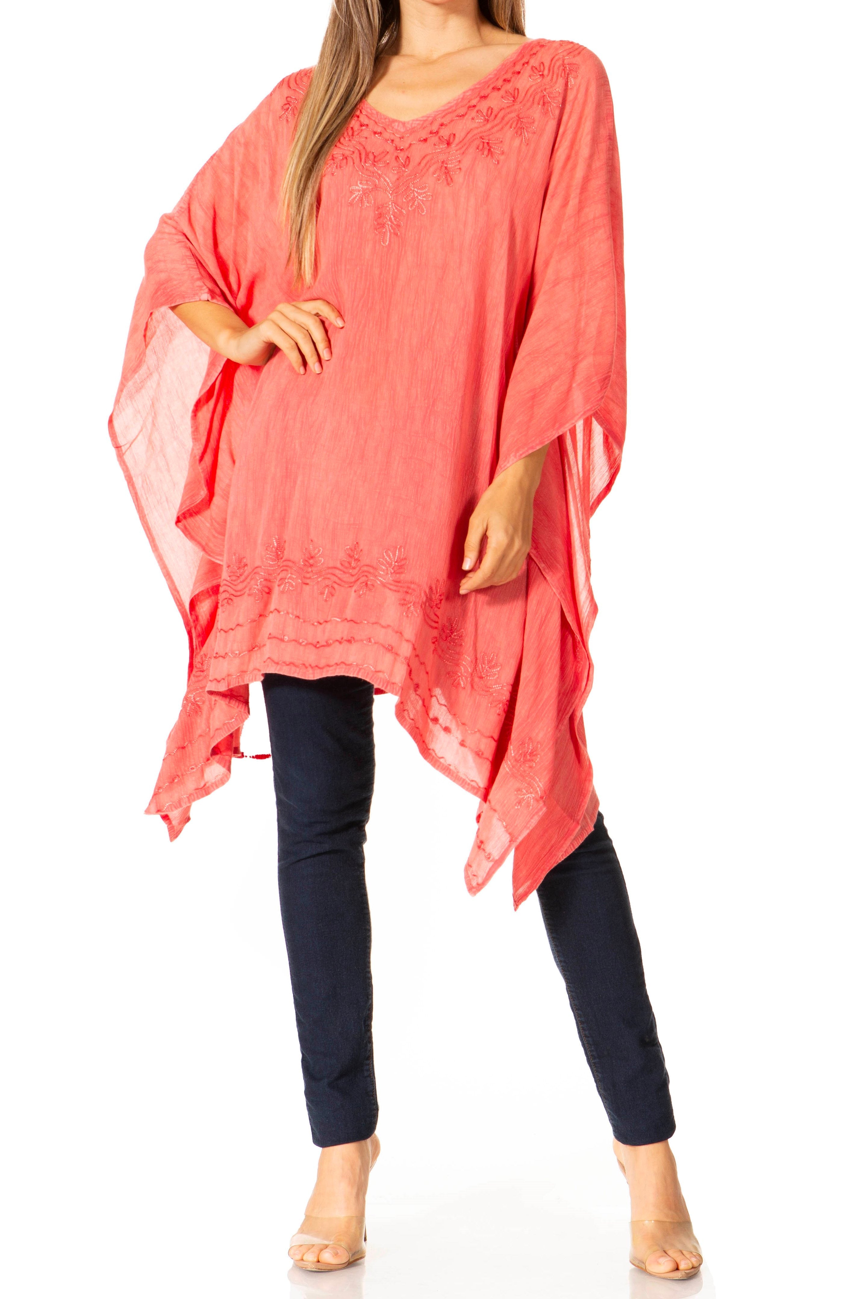 Woman wearing a coral pink poncho over a navy outfit on a white background