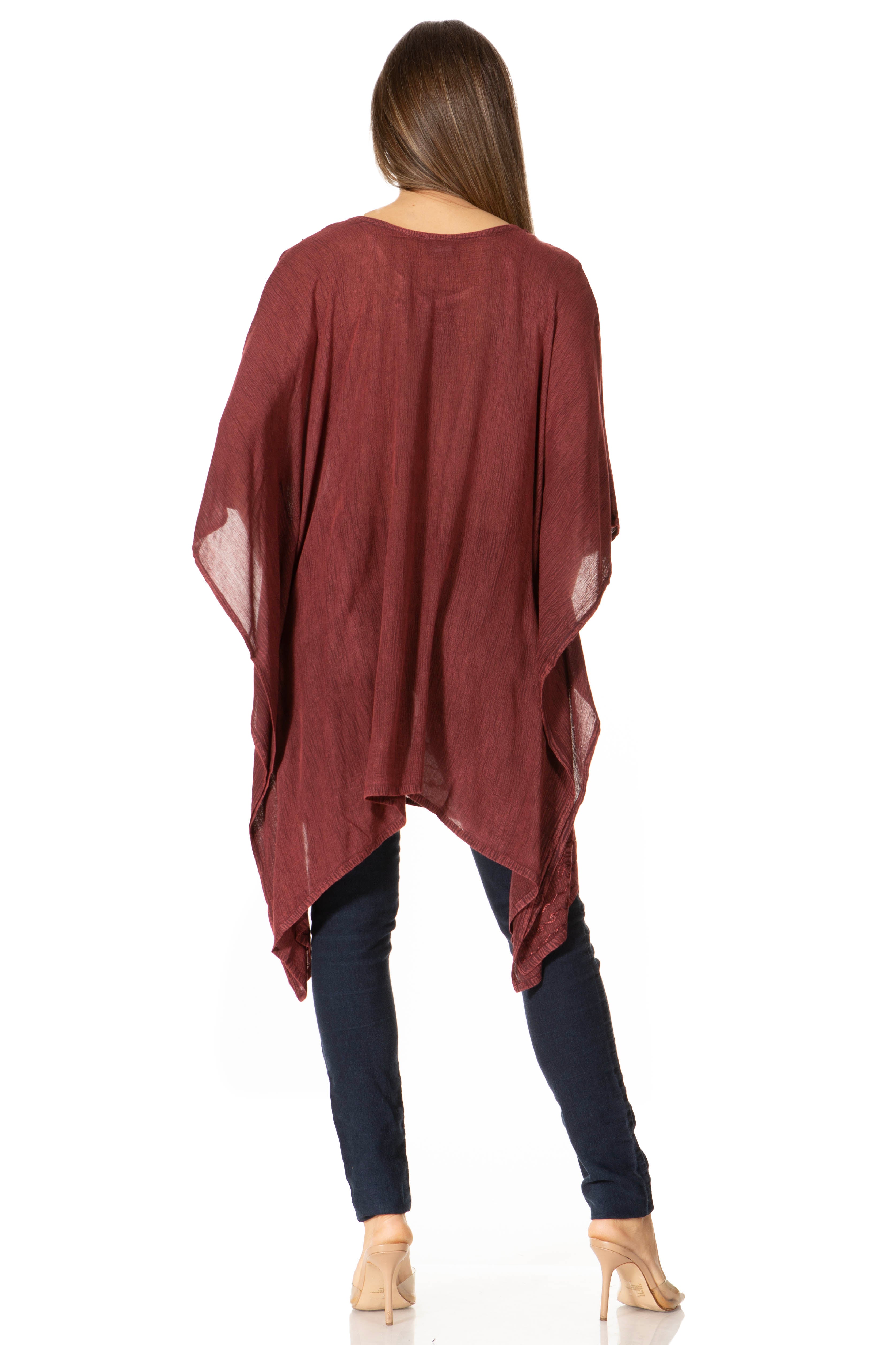 Woman wearing a burgundy poncho over dark pants on a white background