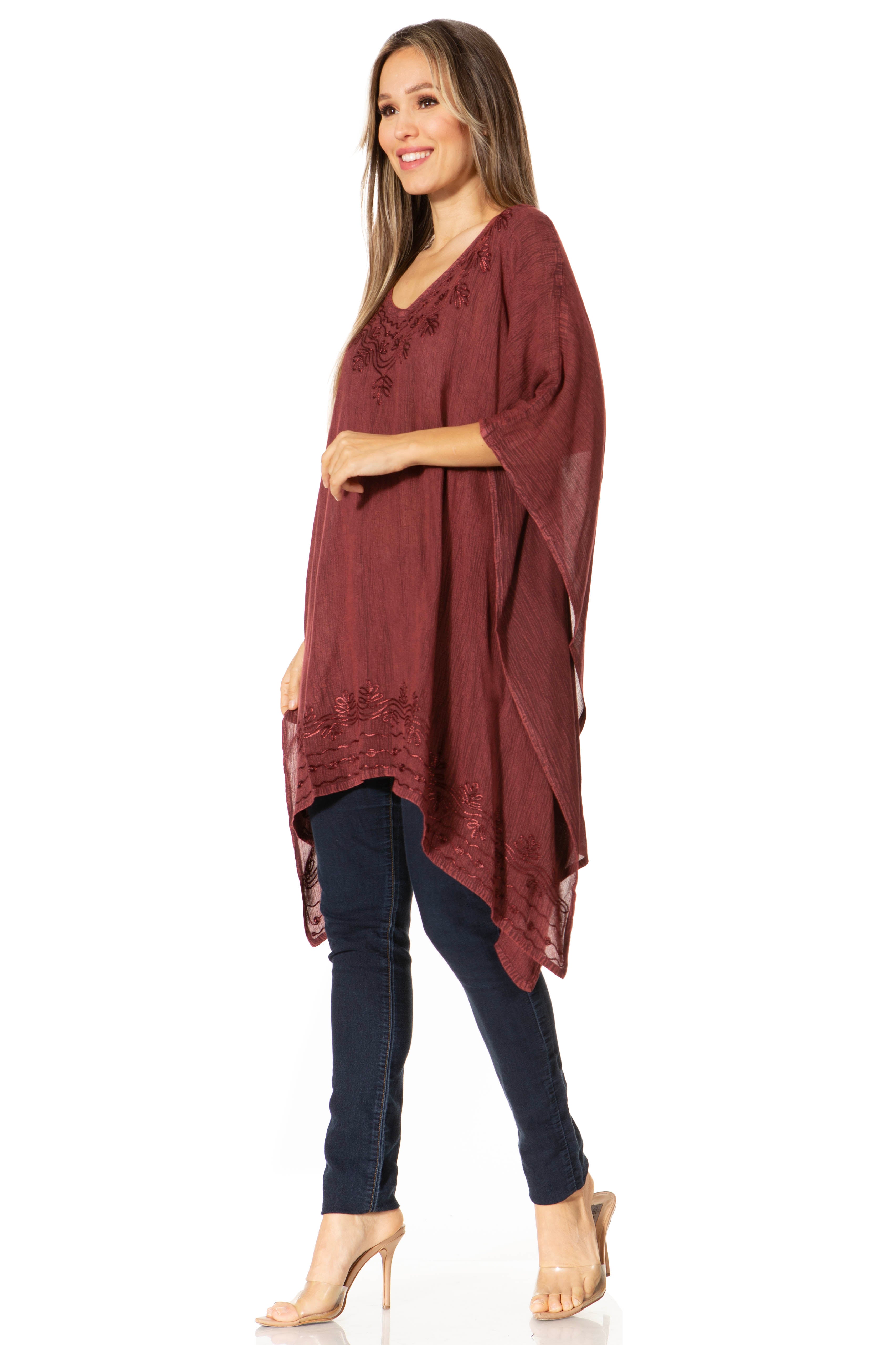Woman wearing a burgundy lace top and dark jeans on a white background