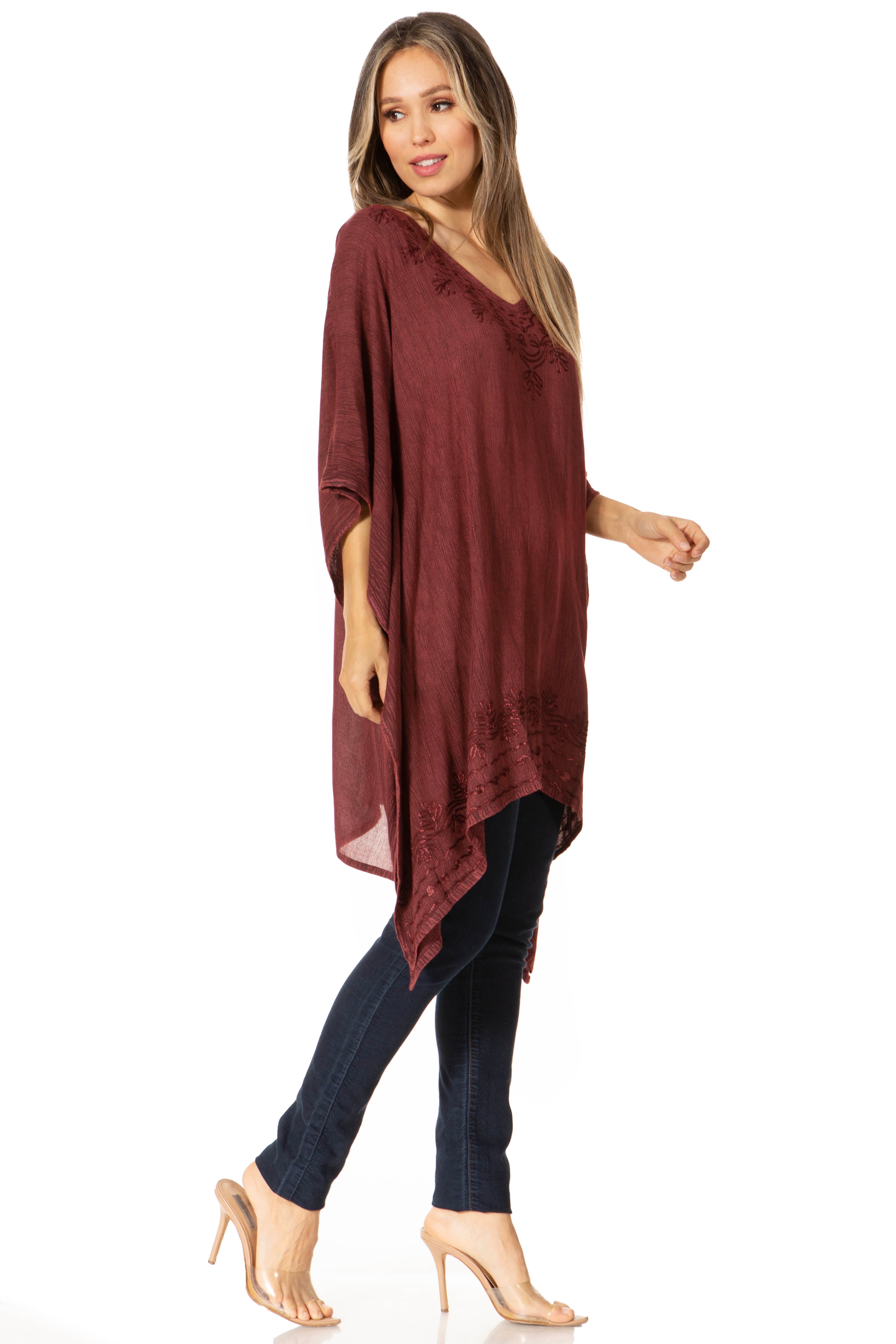 Woman wearing a burgundy oversized top and dark jeans on a white background