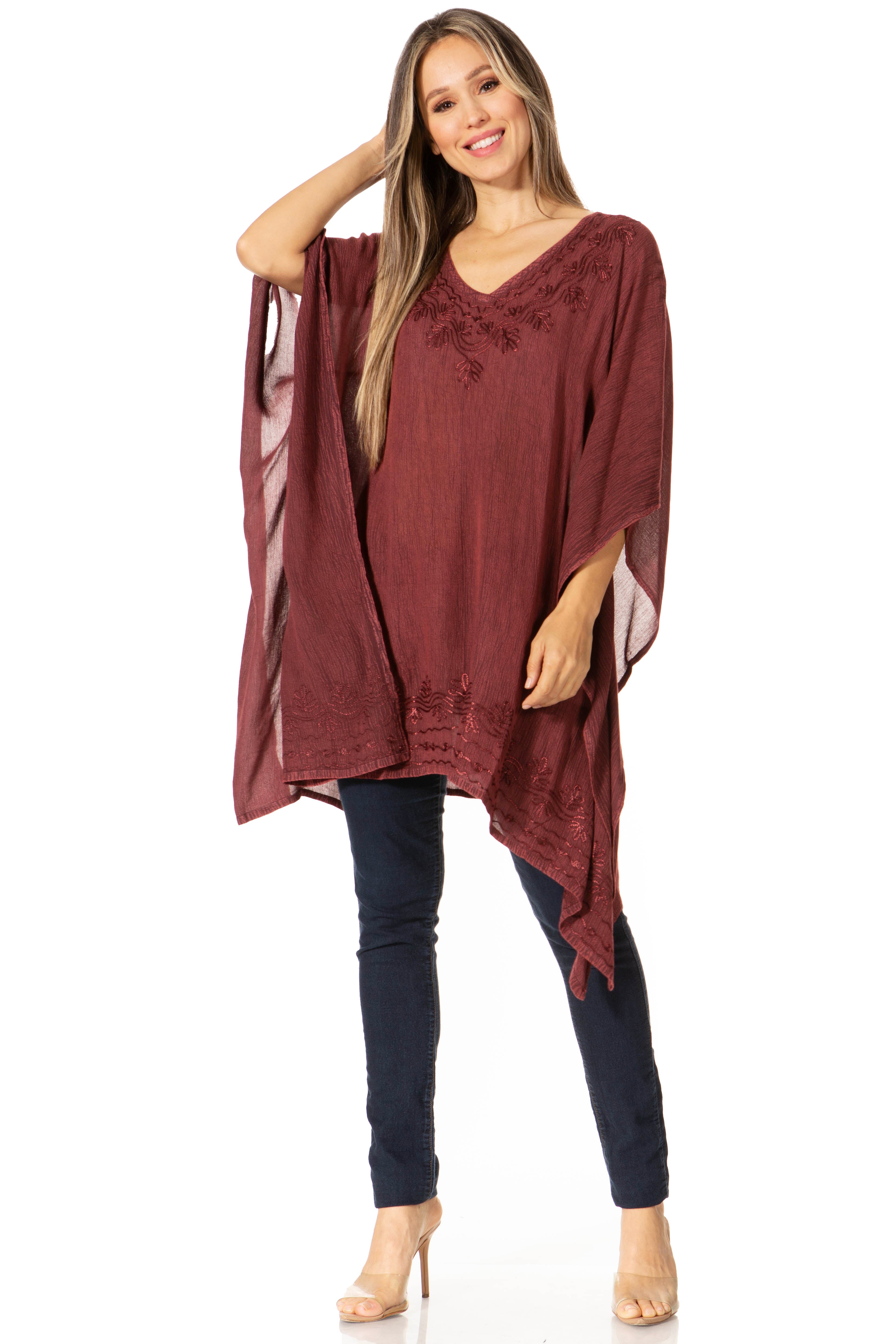 Woman wearing a burgundy poncho over a dark outfit on a white background