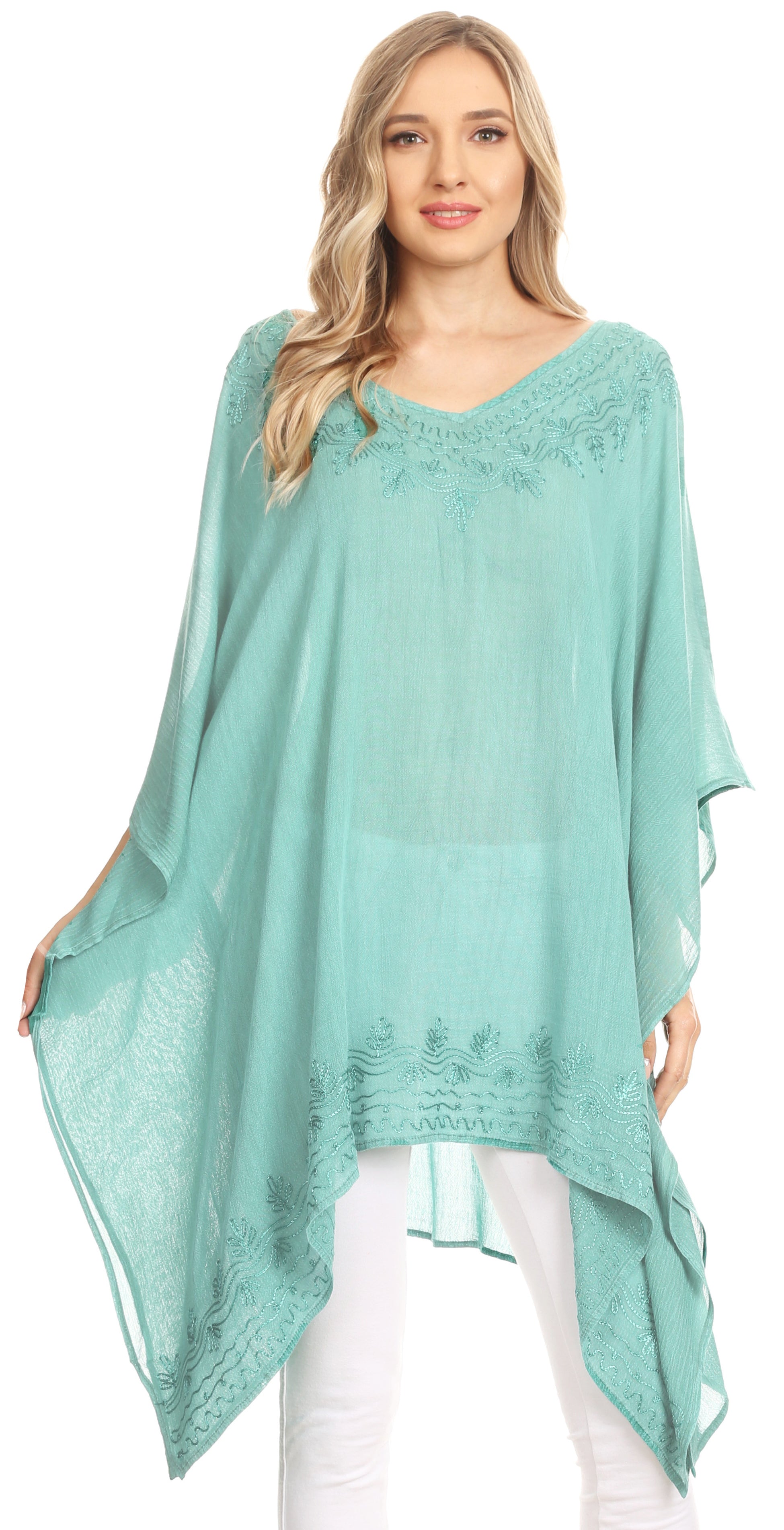 Woman wearing a teal poncho with lace details on a white background