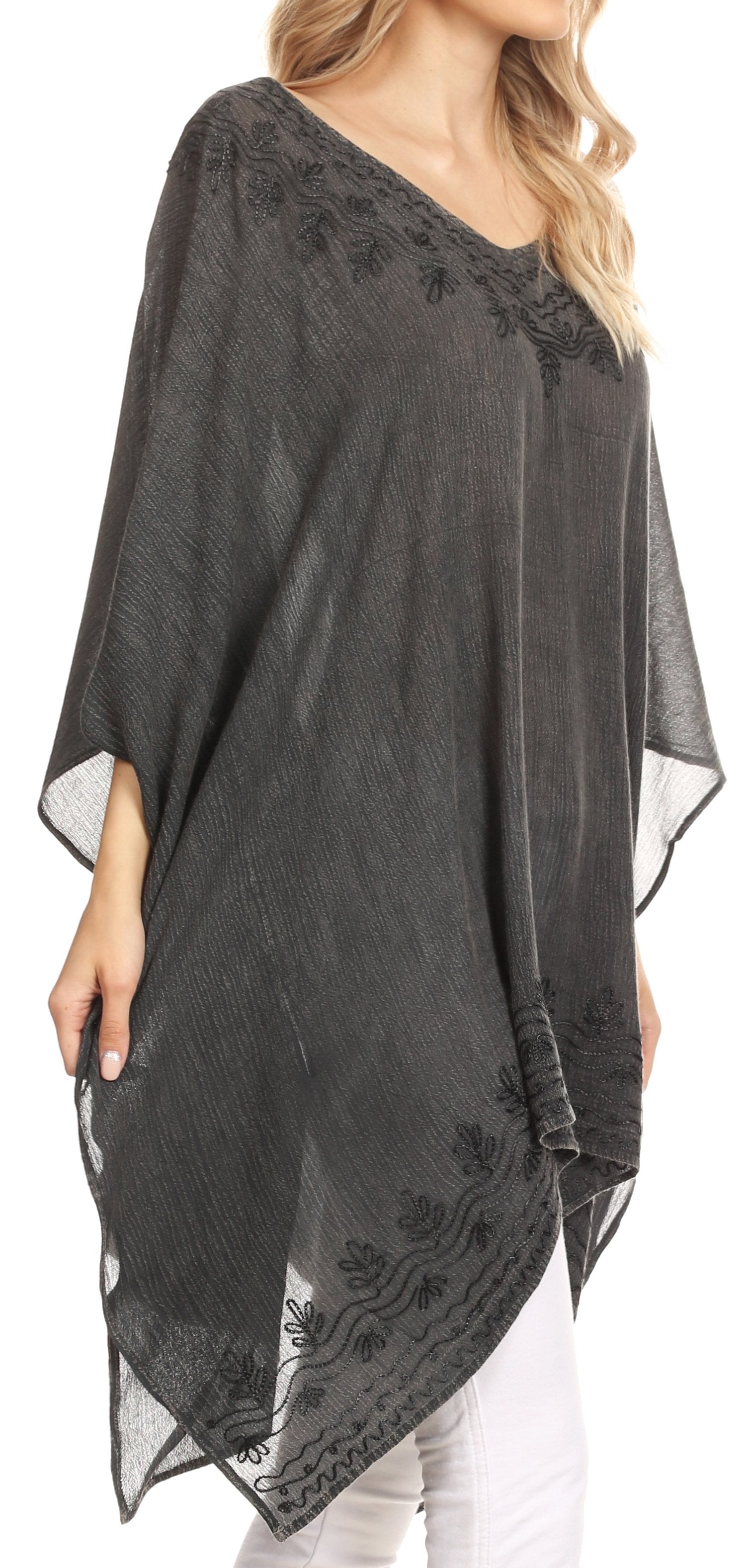 Woman wearing a dark gray poncho with floral embroidery on a white background