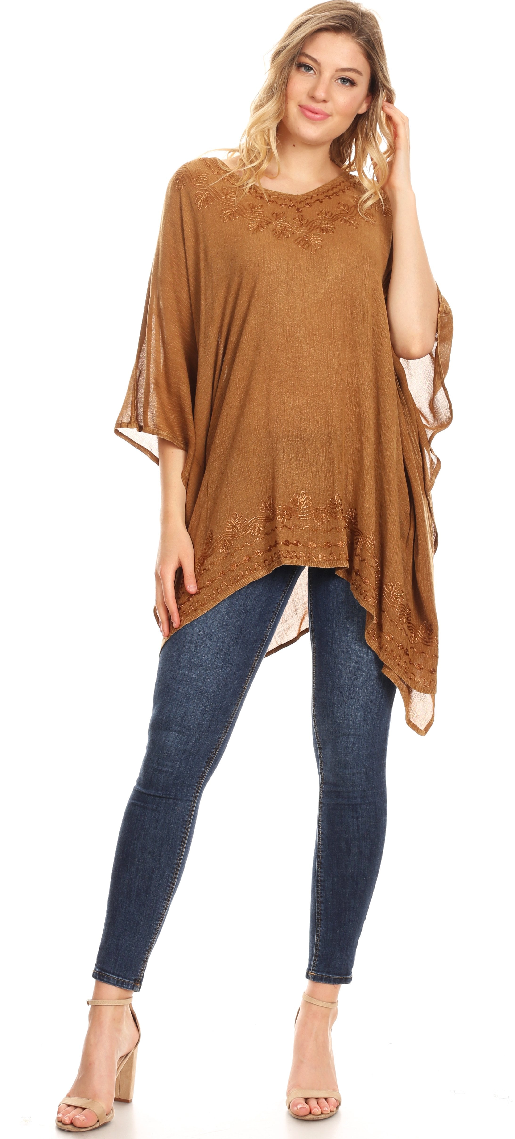 Woman wearing a brown poncho and blue jeans on a white background