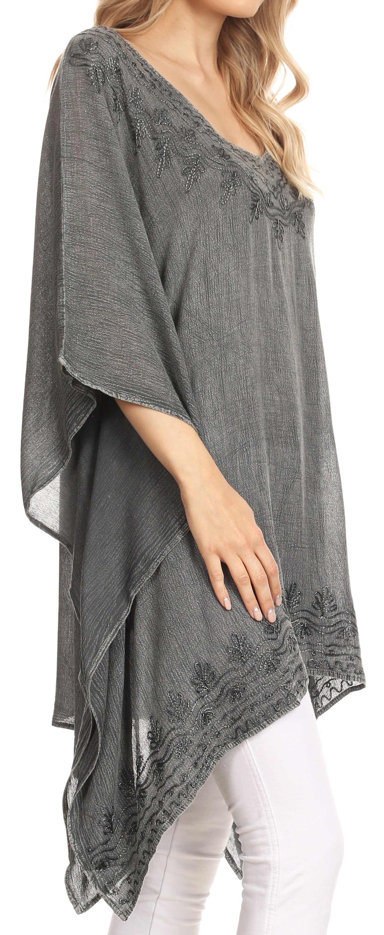 Gray poncho with lace details worn by a person, with white pants underneath.