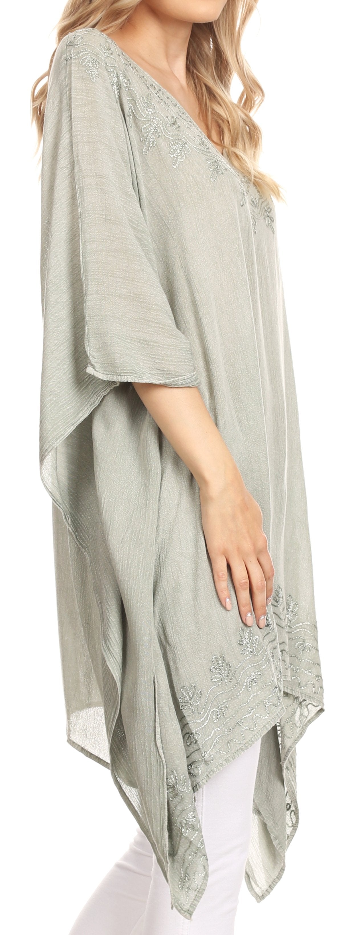 Light green poncho with lace details worn by a person on a white background