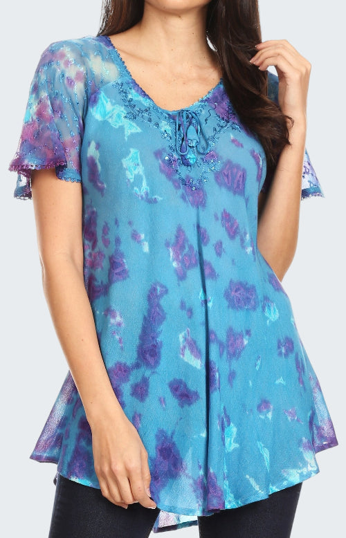 Woman wearing a blue and purple floral blouse with ruffled sleeves.