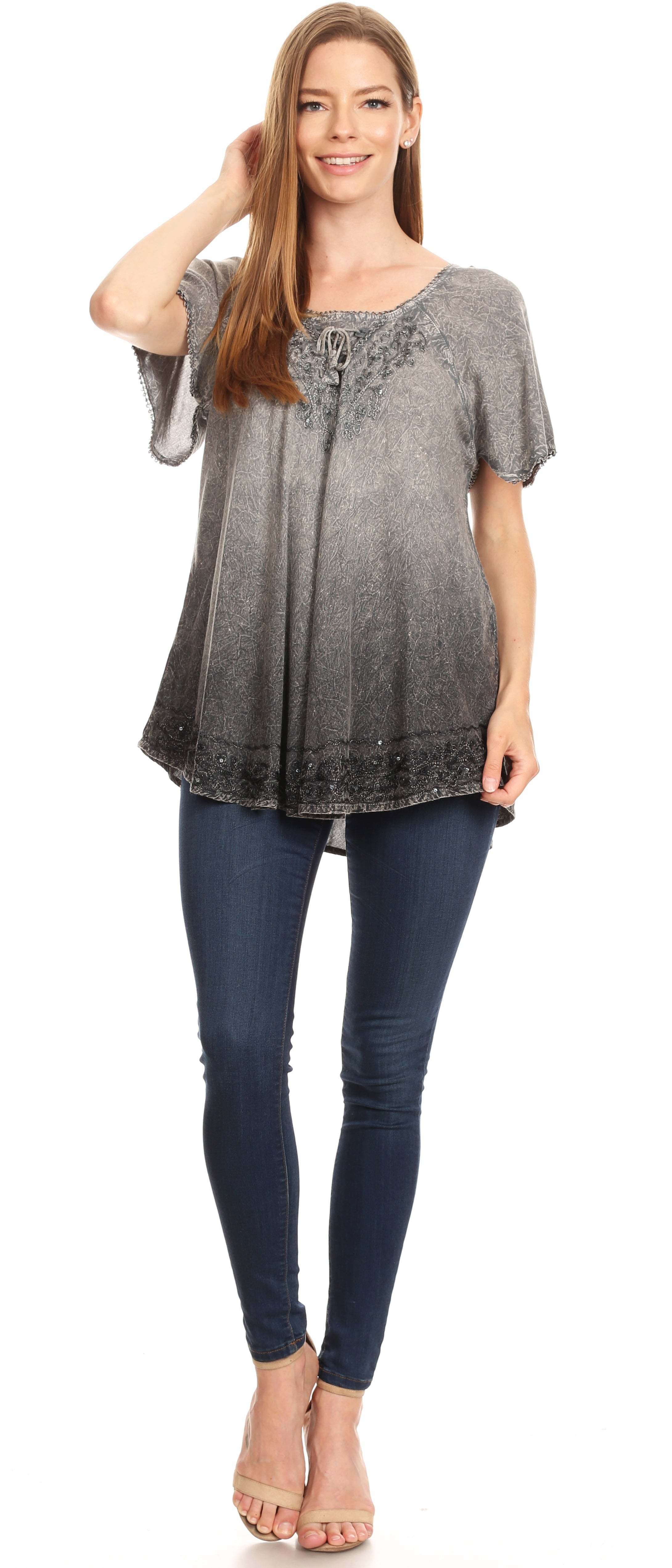 Woman wearing a gray gradient top with lace details and blue jeans on a white background