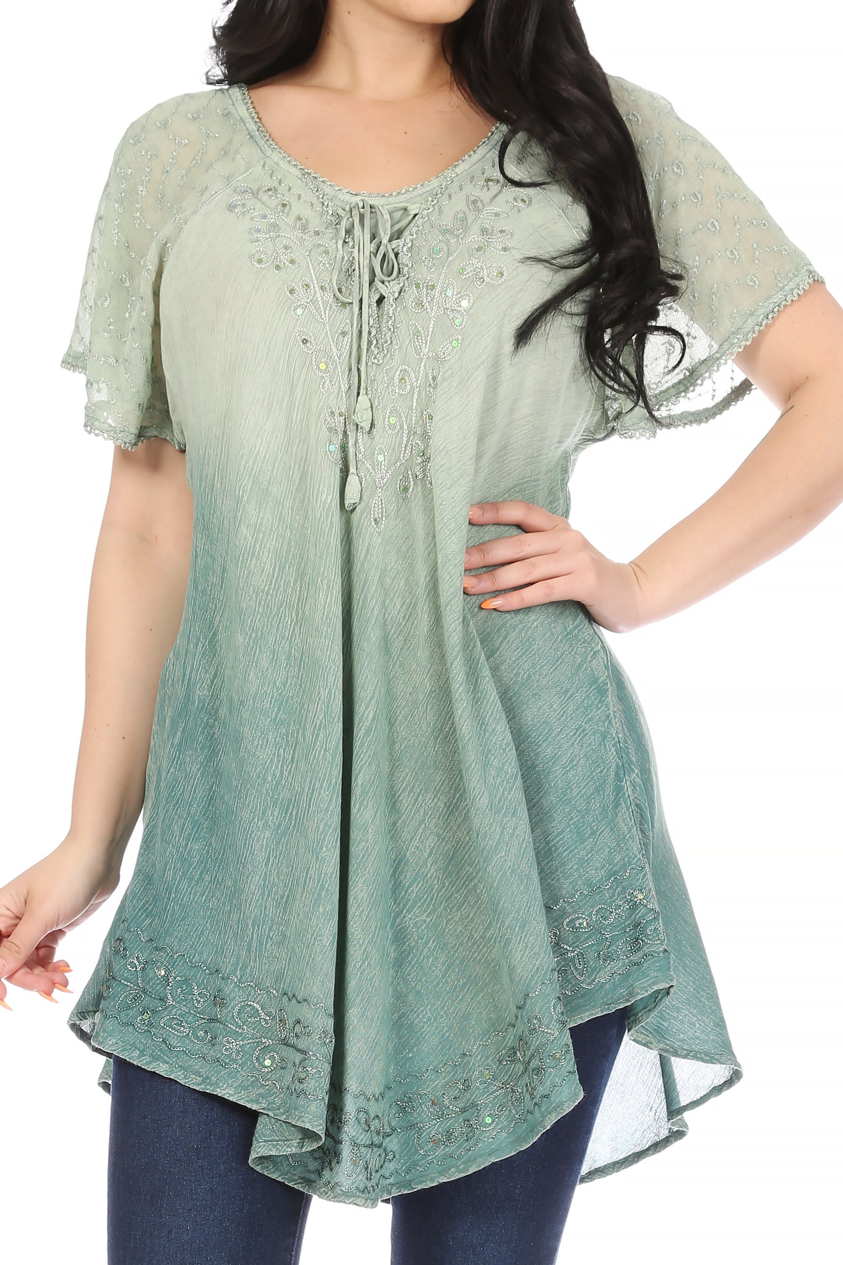 Woman wearing a light green lace-up top with short sleeves and blue pants.