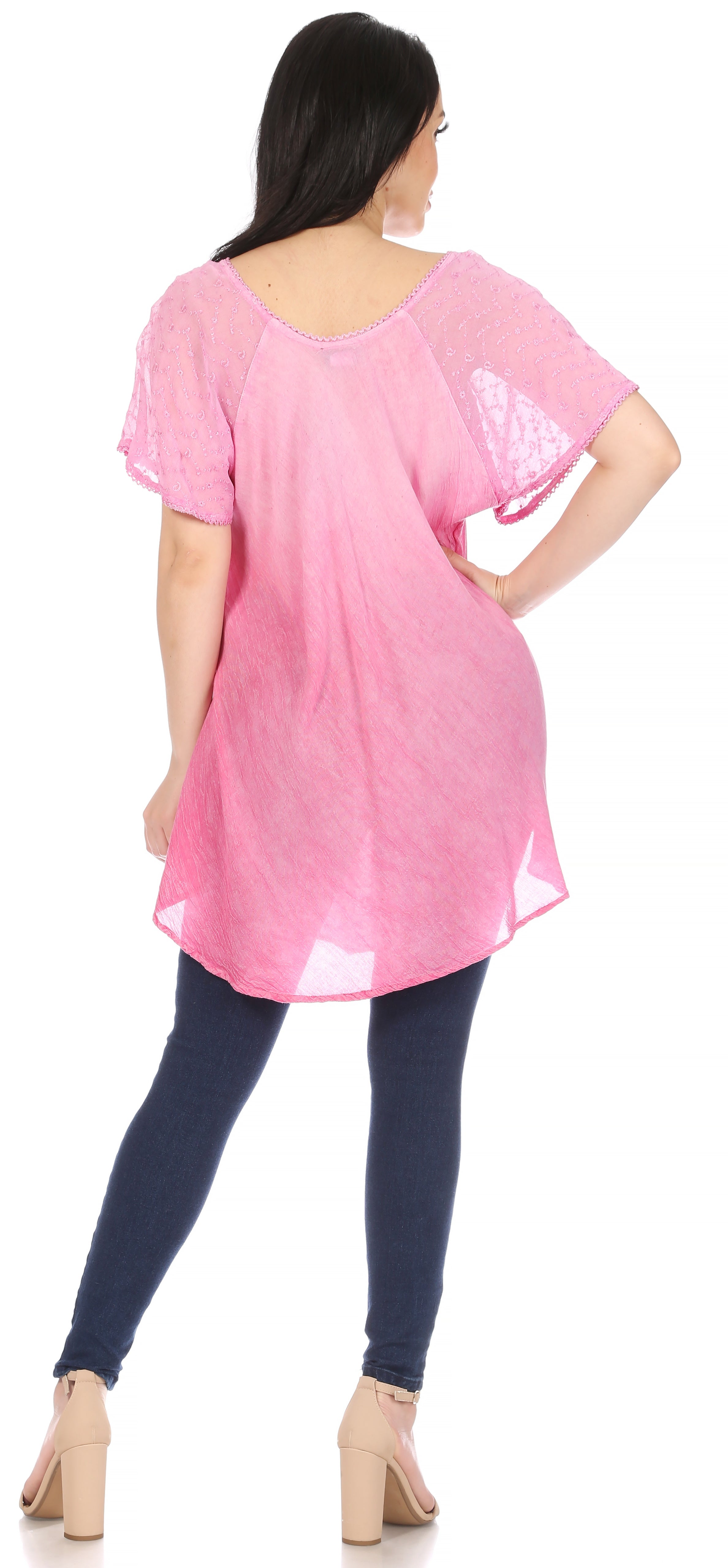 Woman wearing a pink tunic and dark blue leggings on a white background