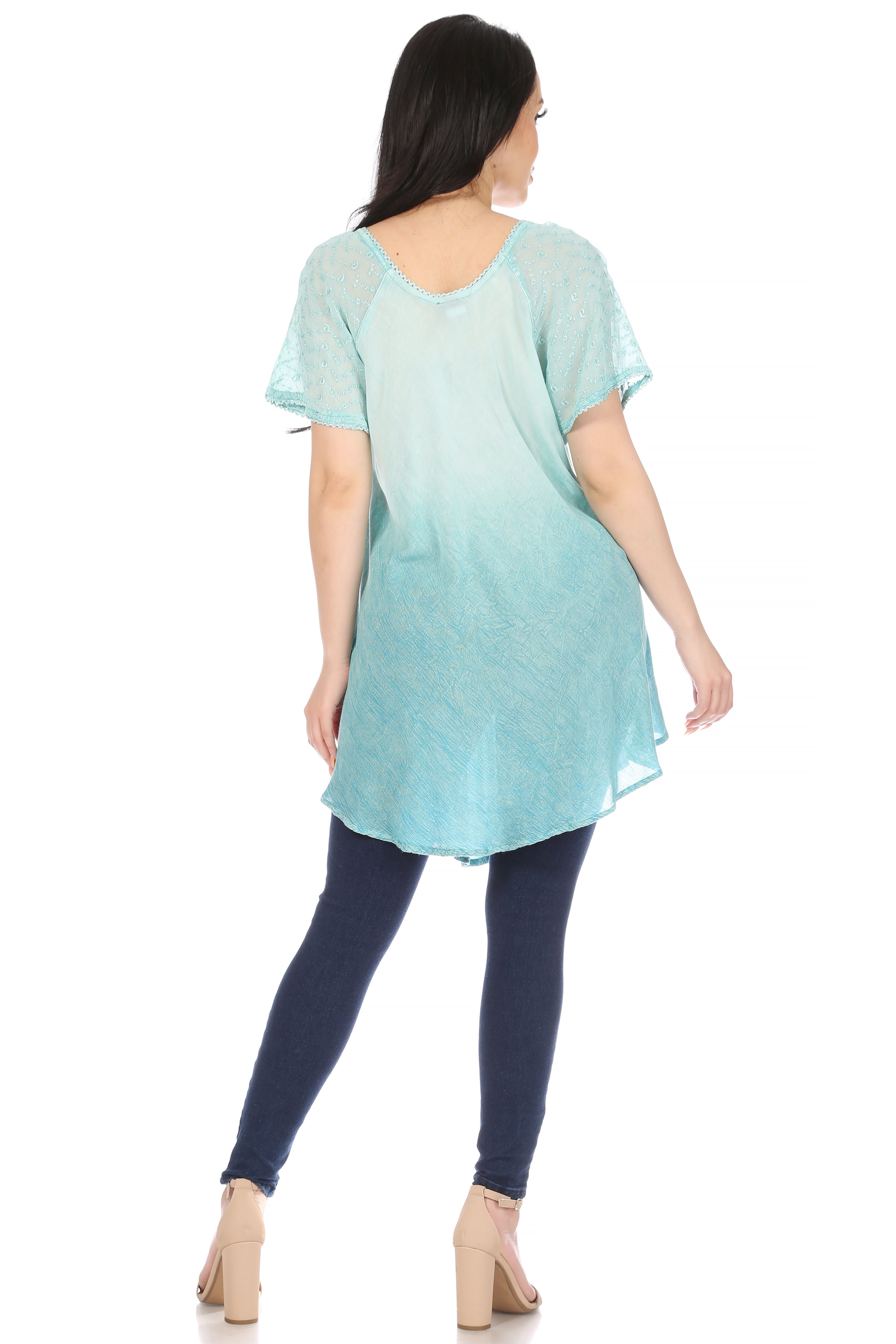 Woman wearing a light blue tunic and dark blue leggings on a white background
