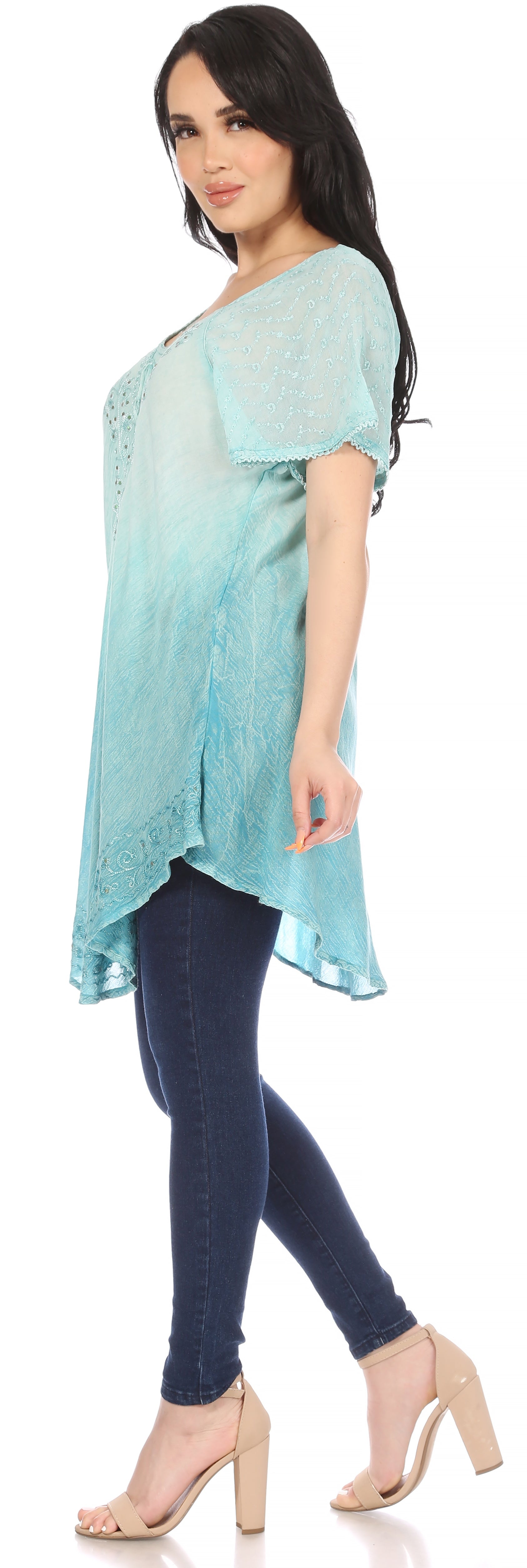 Woman wearing a light blue top and dark blue jeans on a white background
