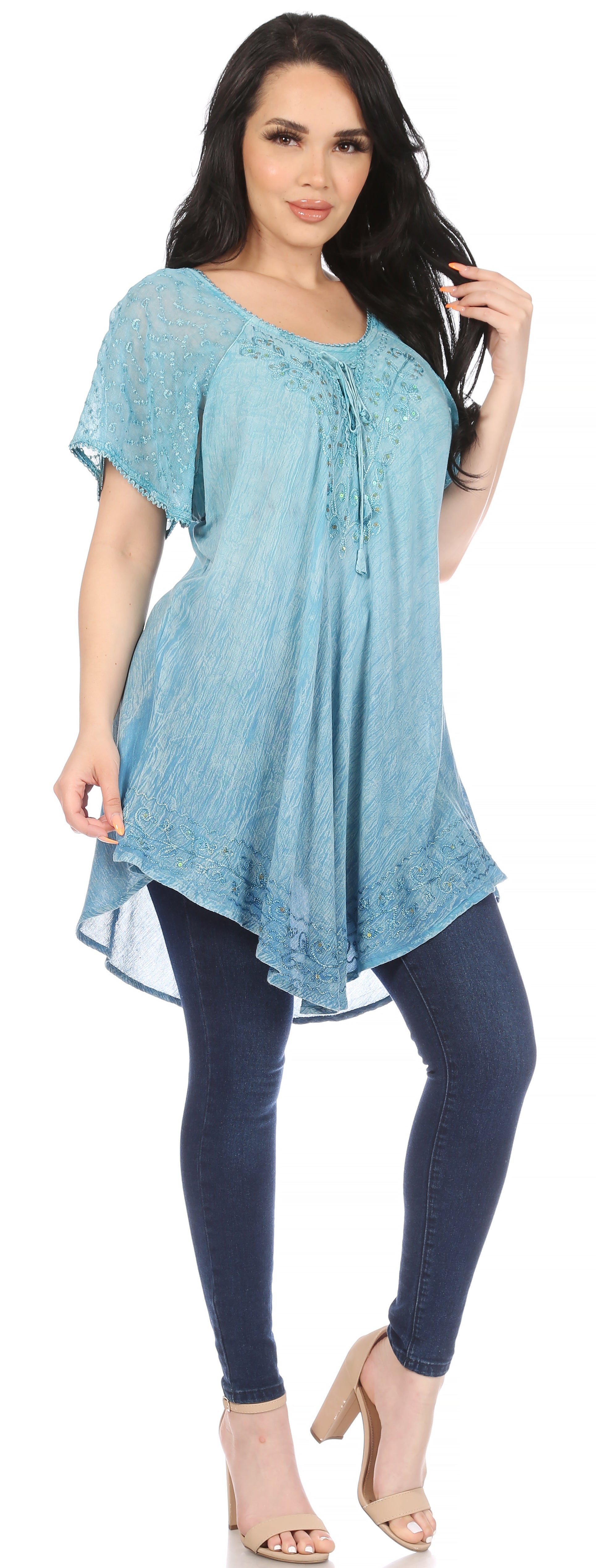 Woman wearing a light blue tunic and dark blue leggings on a white background