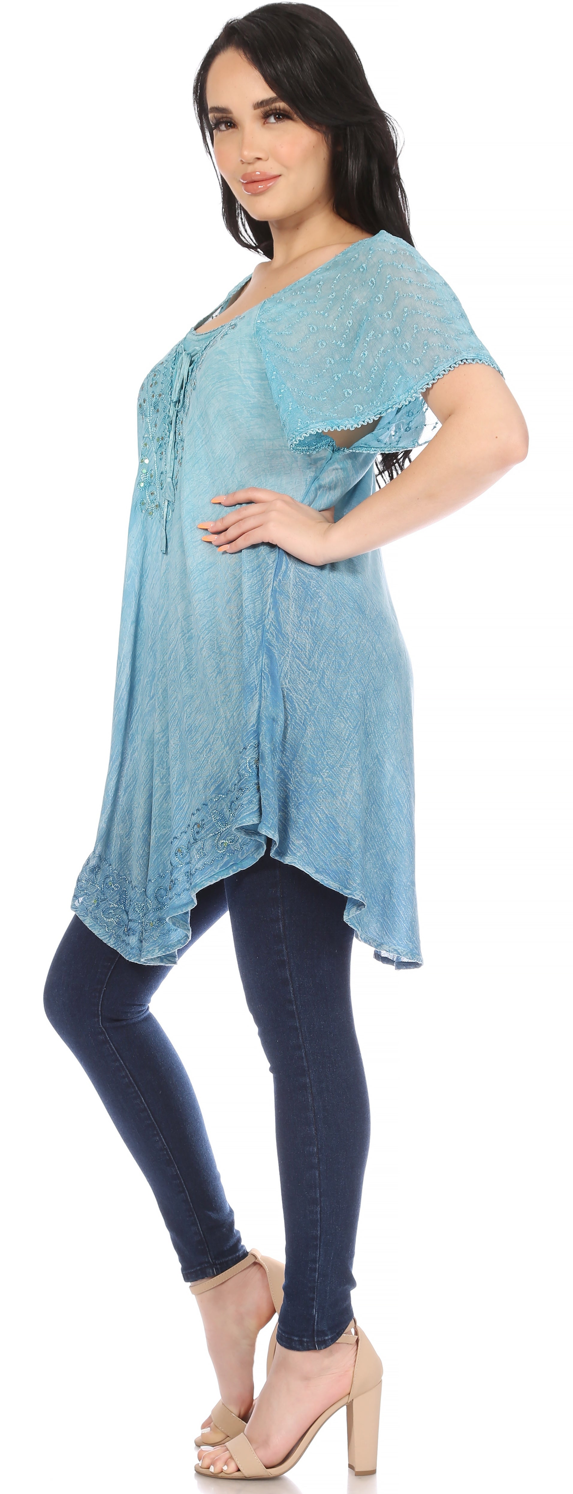 Woman wearing a light blue tunic and dark blue leggings on a white background