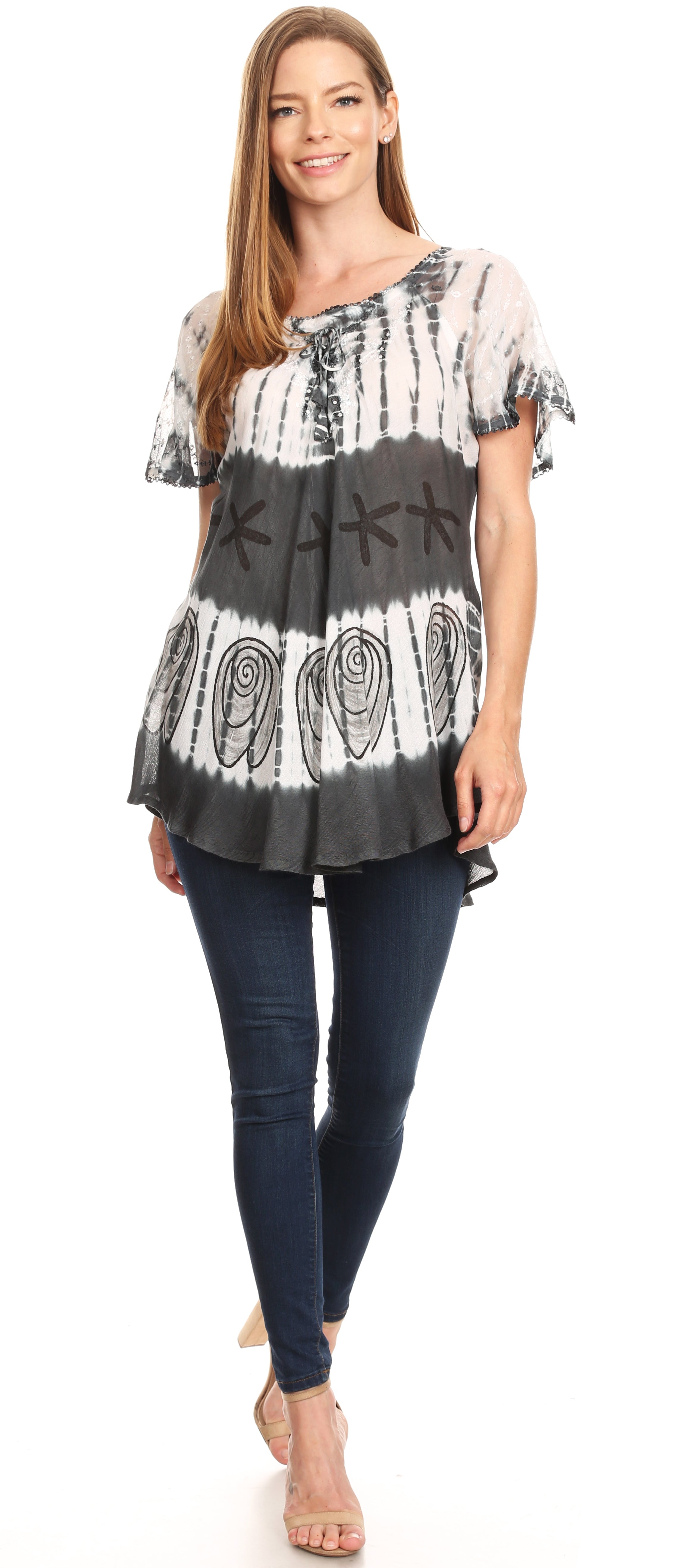 Woman wearing a black and white patterned top with blue jeans on a white background