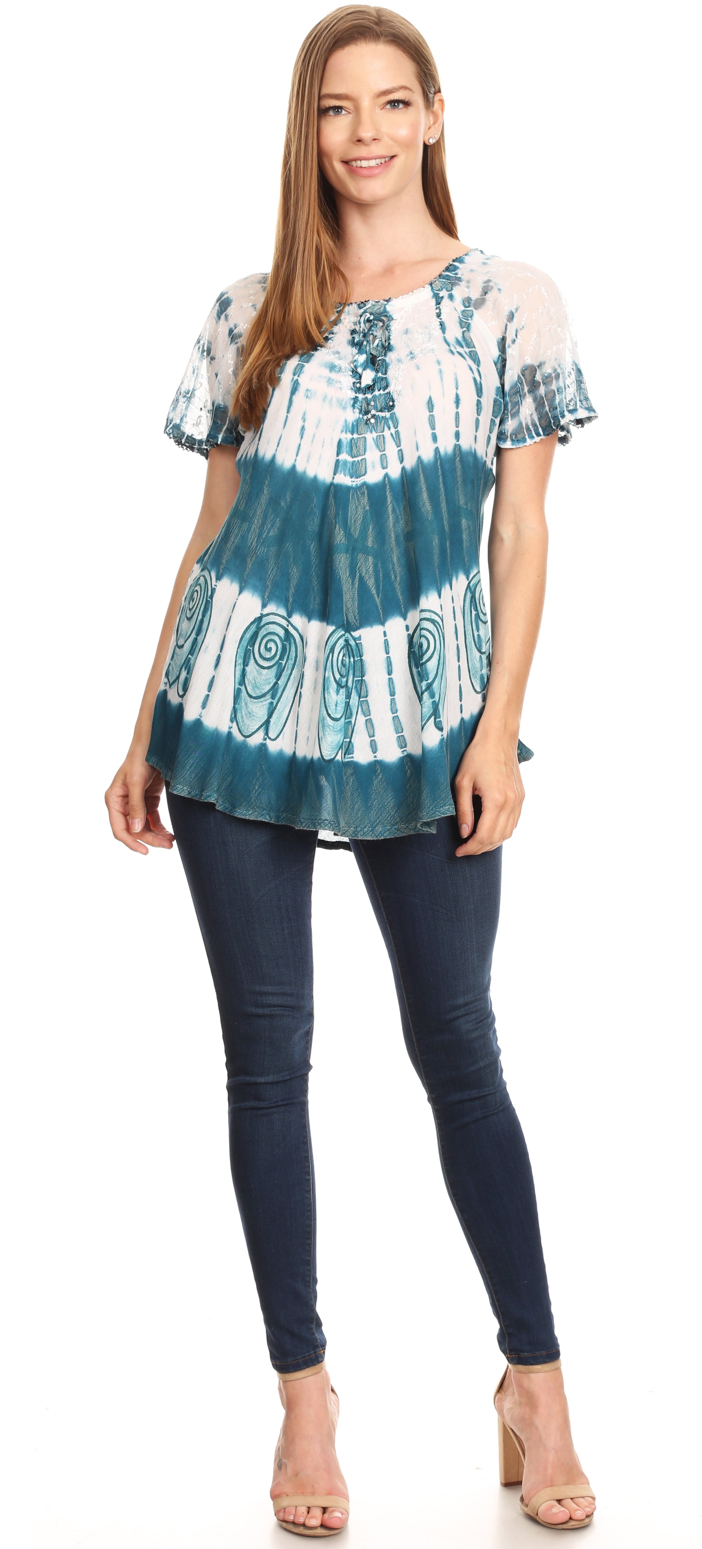 Woman wearing a blue and white patterned top with dark jeans on a white background