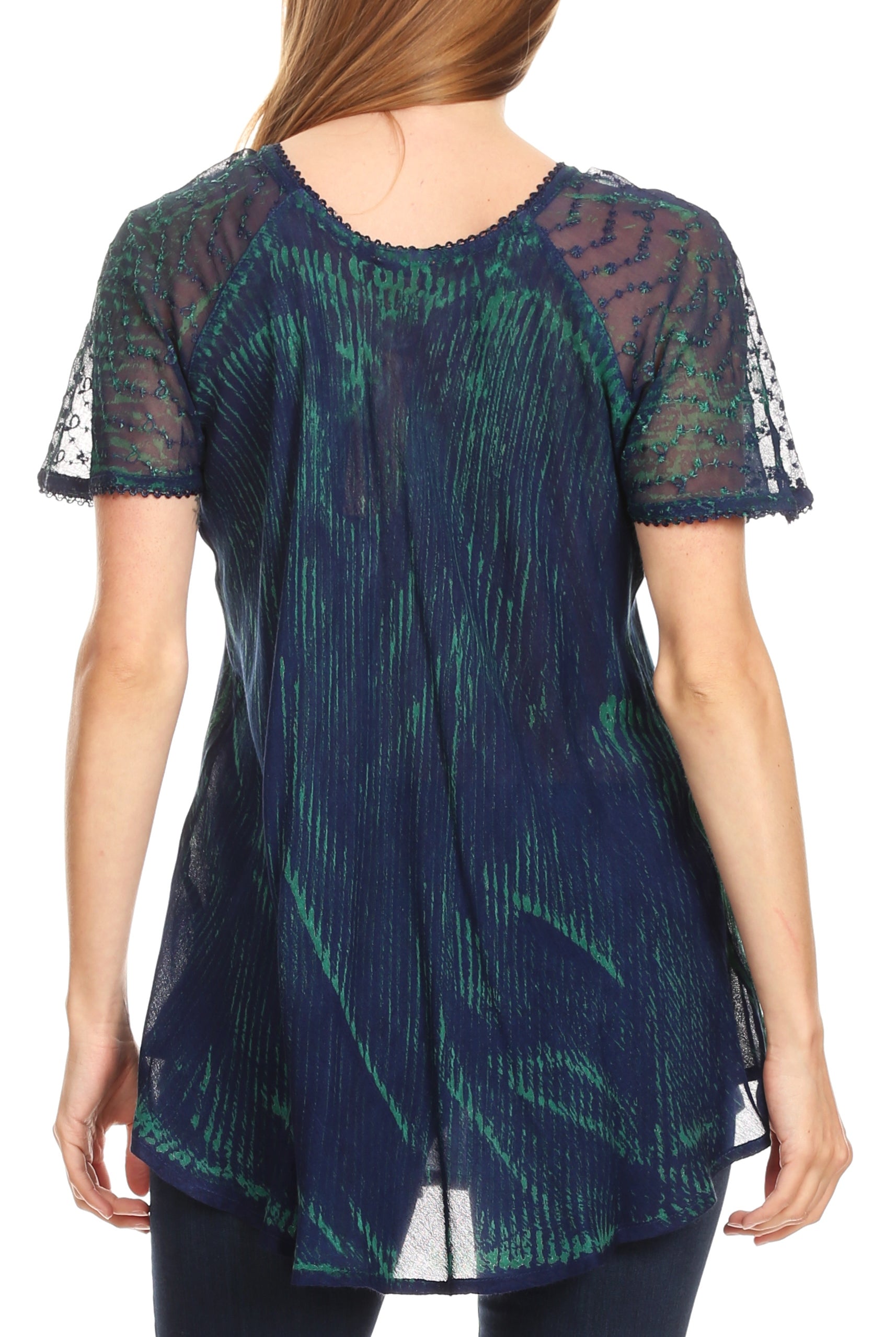 Woman wearing a dark blue and green patterned top with sheer sleeves on a white background