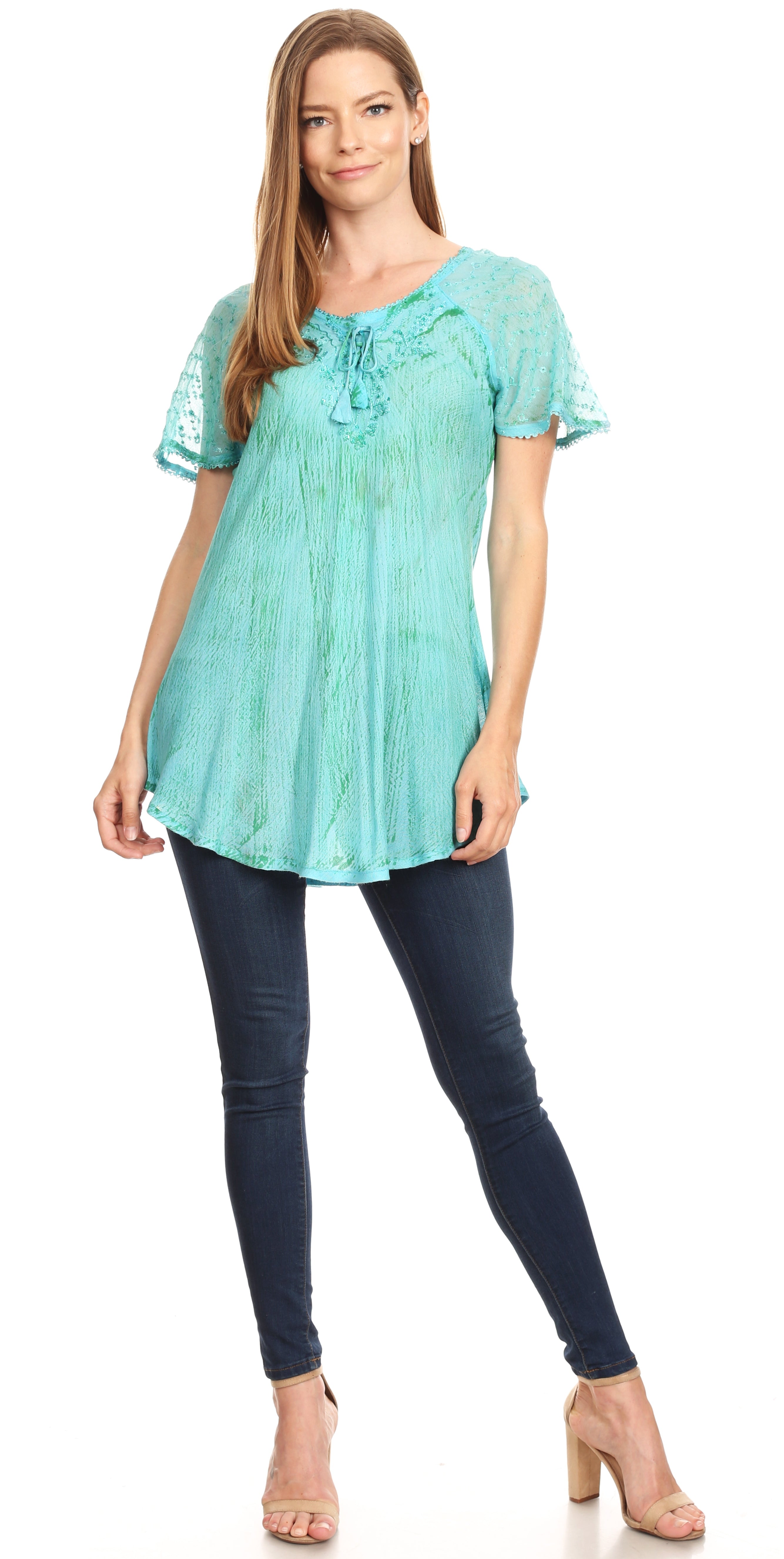 Woman wearing a light blue lace top and dark blue jeans on a white background