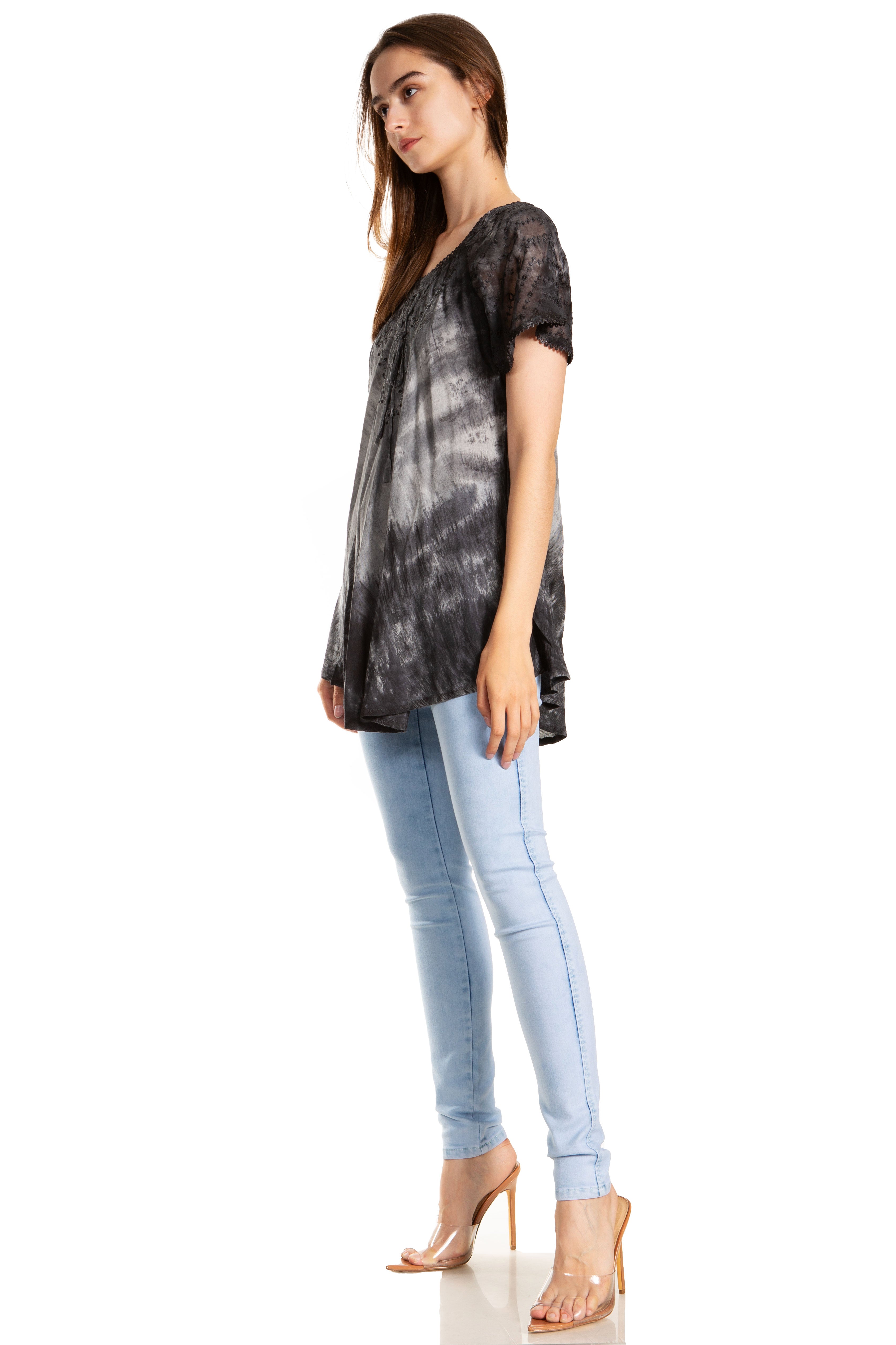 Woman wearing a black tie-dye shirt and light blue jeans on a white background