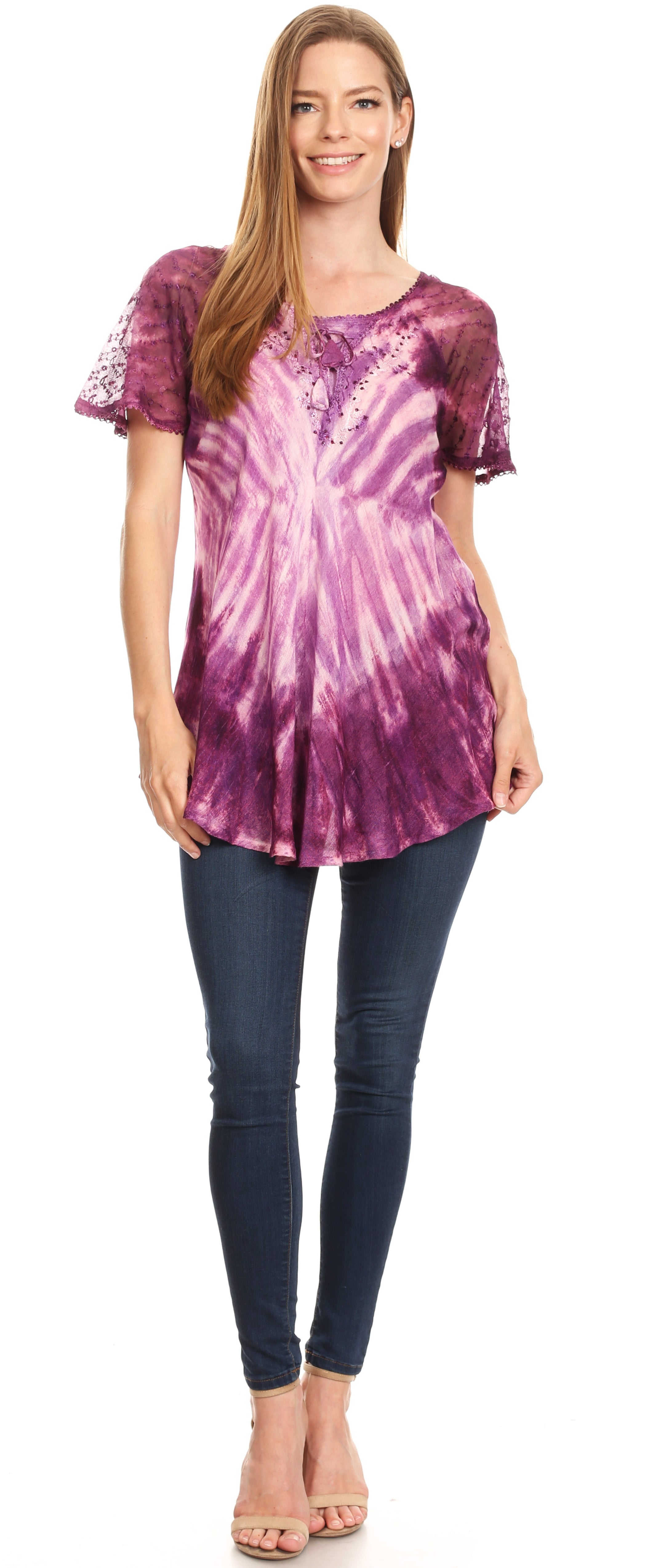 Woman wearing a purple tie-dye top and dark jeans on a white background