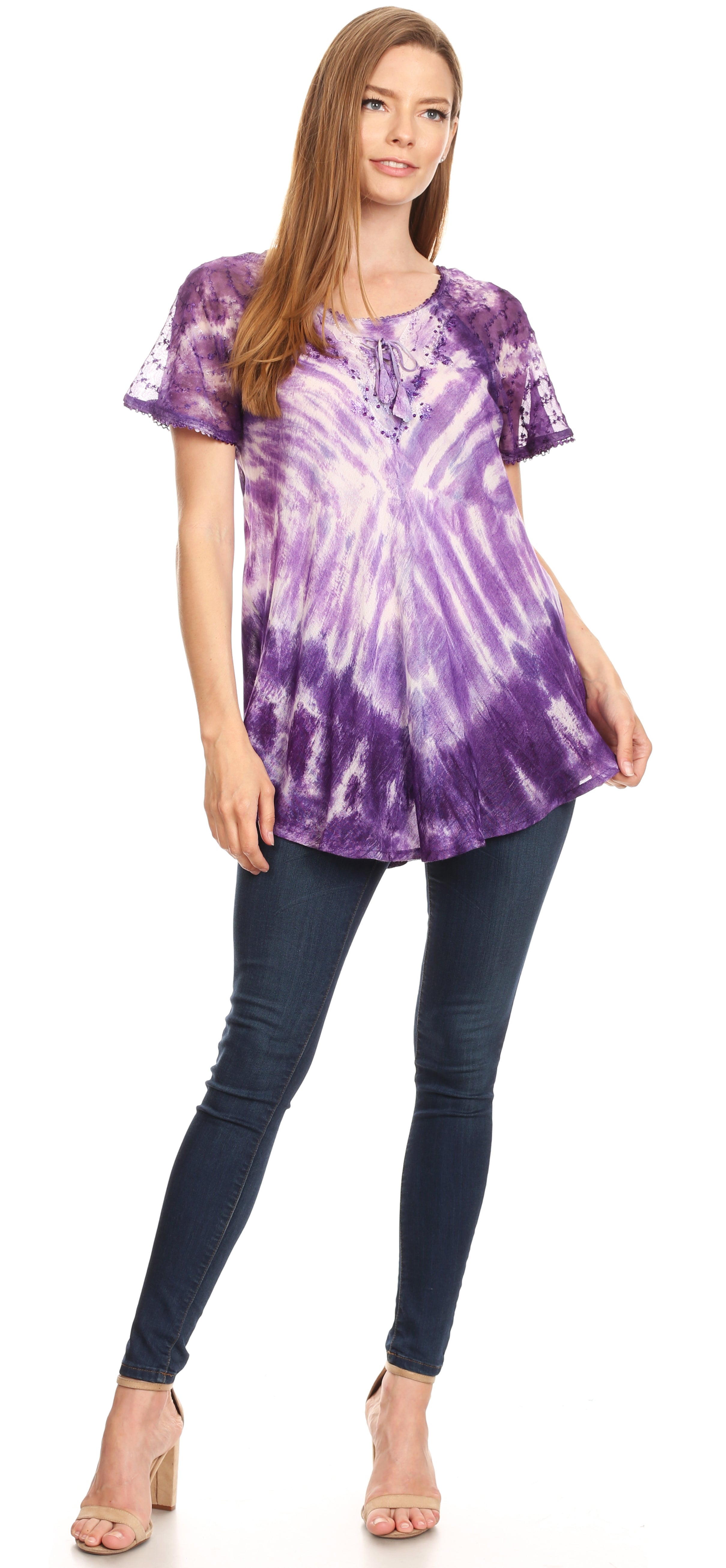 Woman wearing a purple tie-dye shirt and dark jeans on a white background