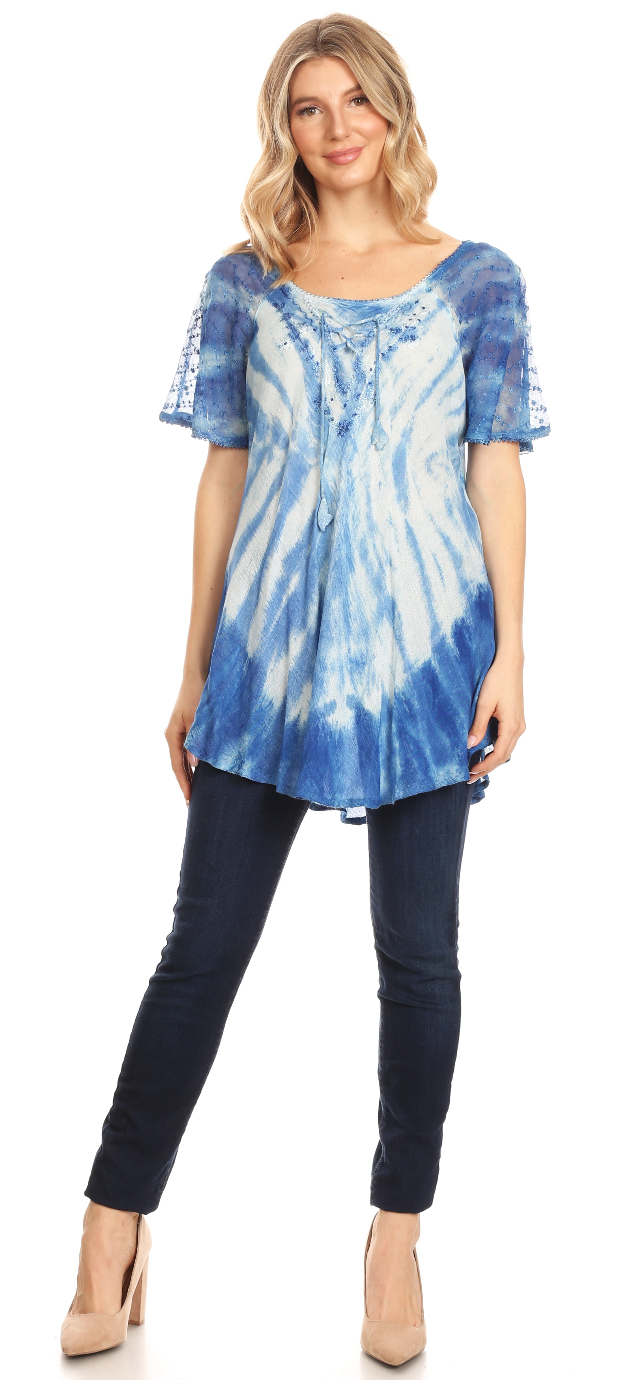 Woman wearing a blue tie-dye top and dark jeans on a white background