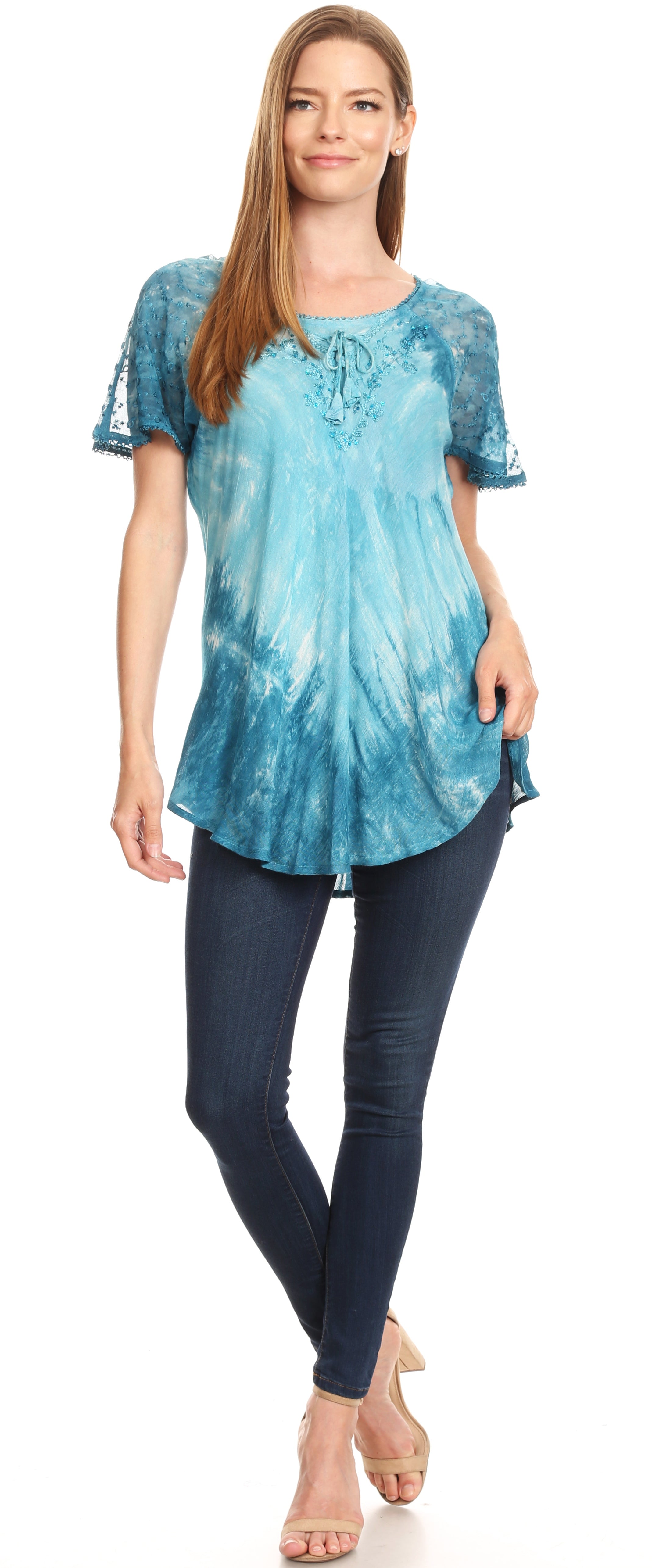 Woman wearing a blue tie-dye top and dark jeans on a white background