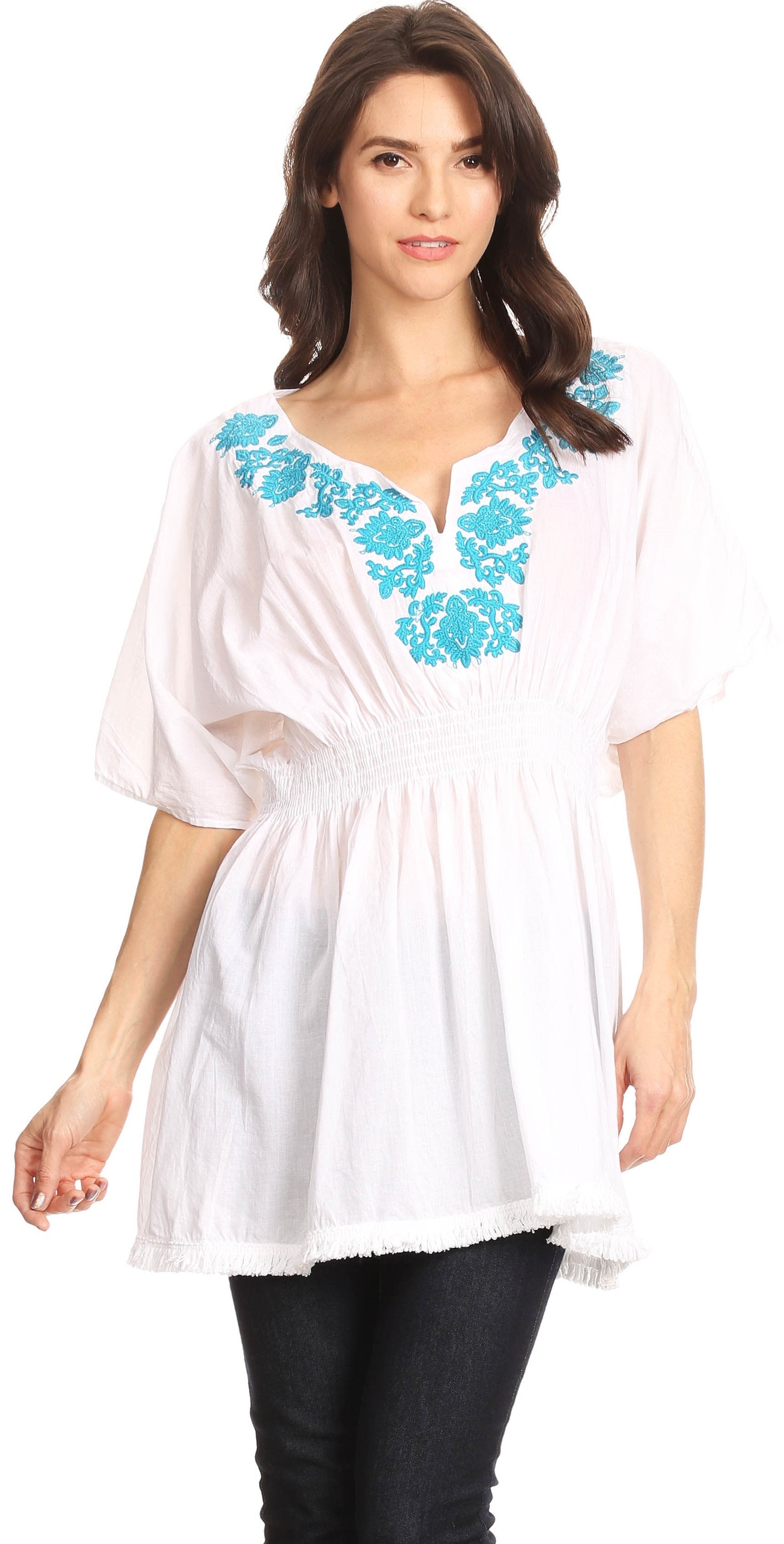 Woman wearing a white blouse with blue floral embroidery on a white background
