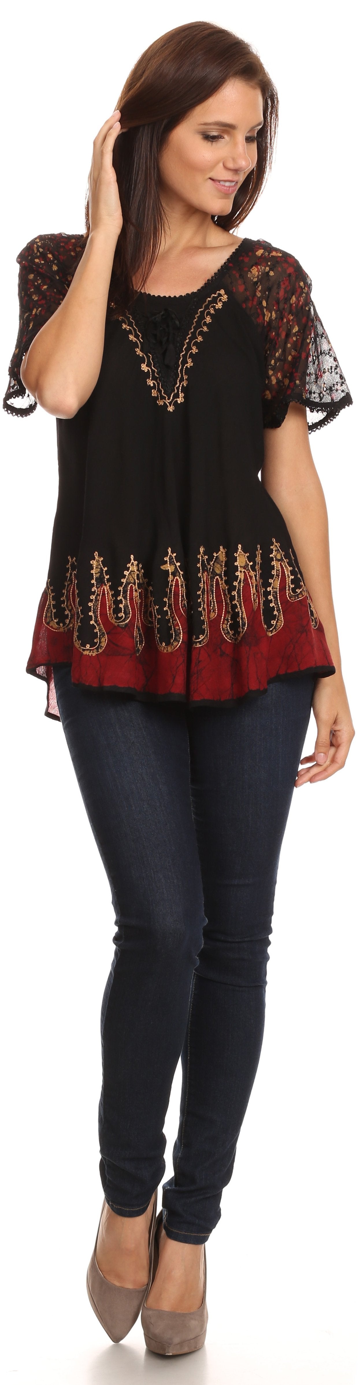 Woman wearing a black top with lace details and dark jeans on a white background