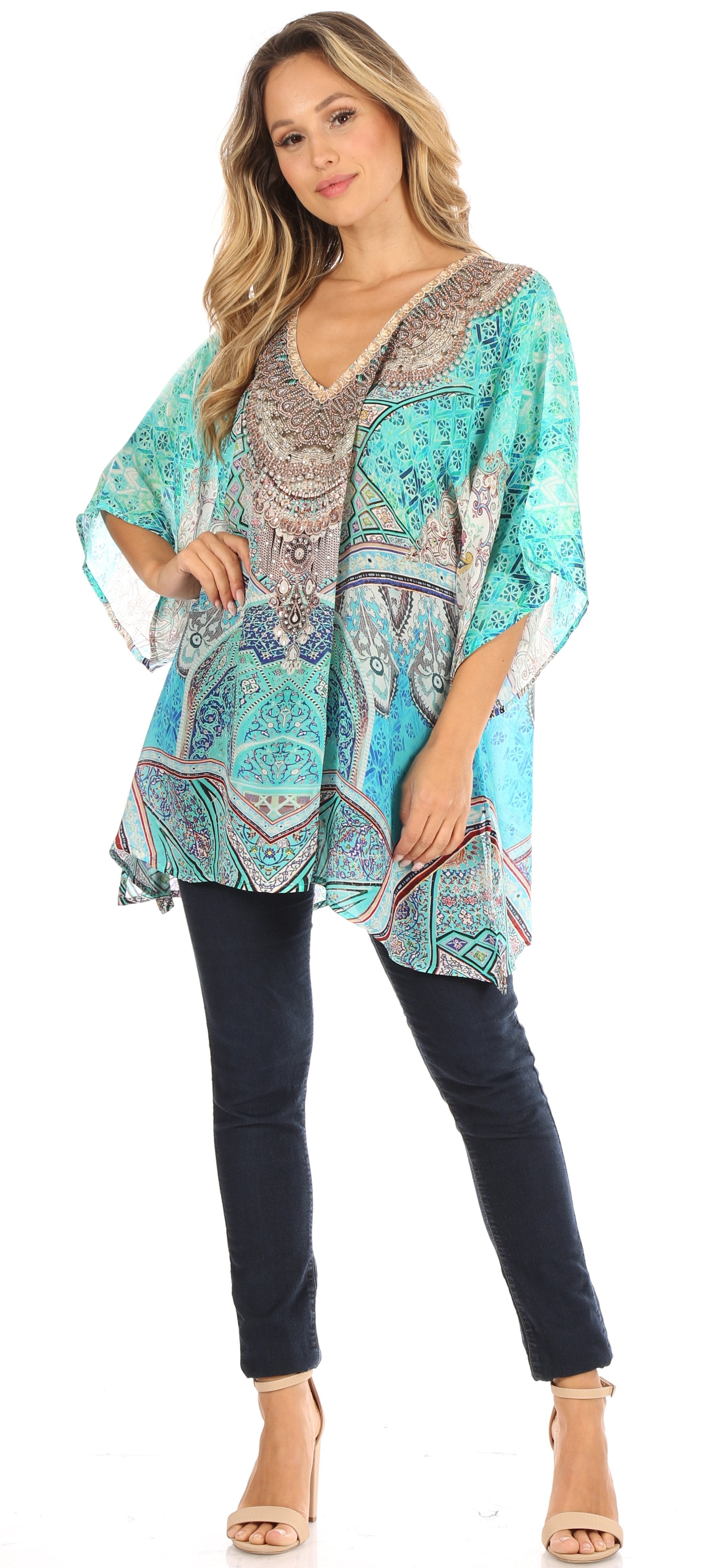 Woman wearing a patterned turquoise top and dark pants on a white background