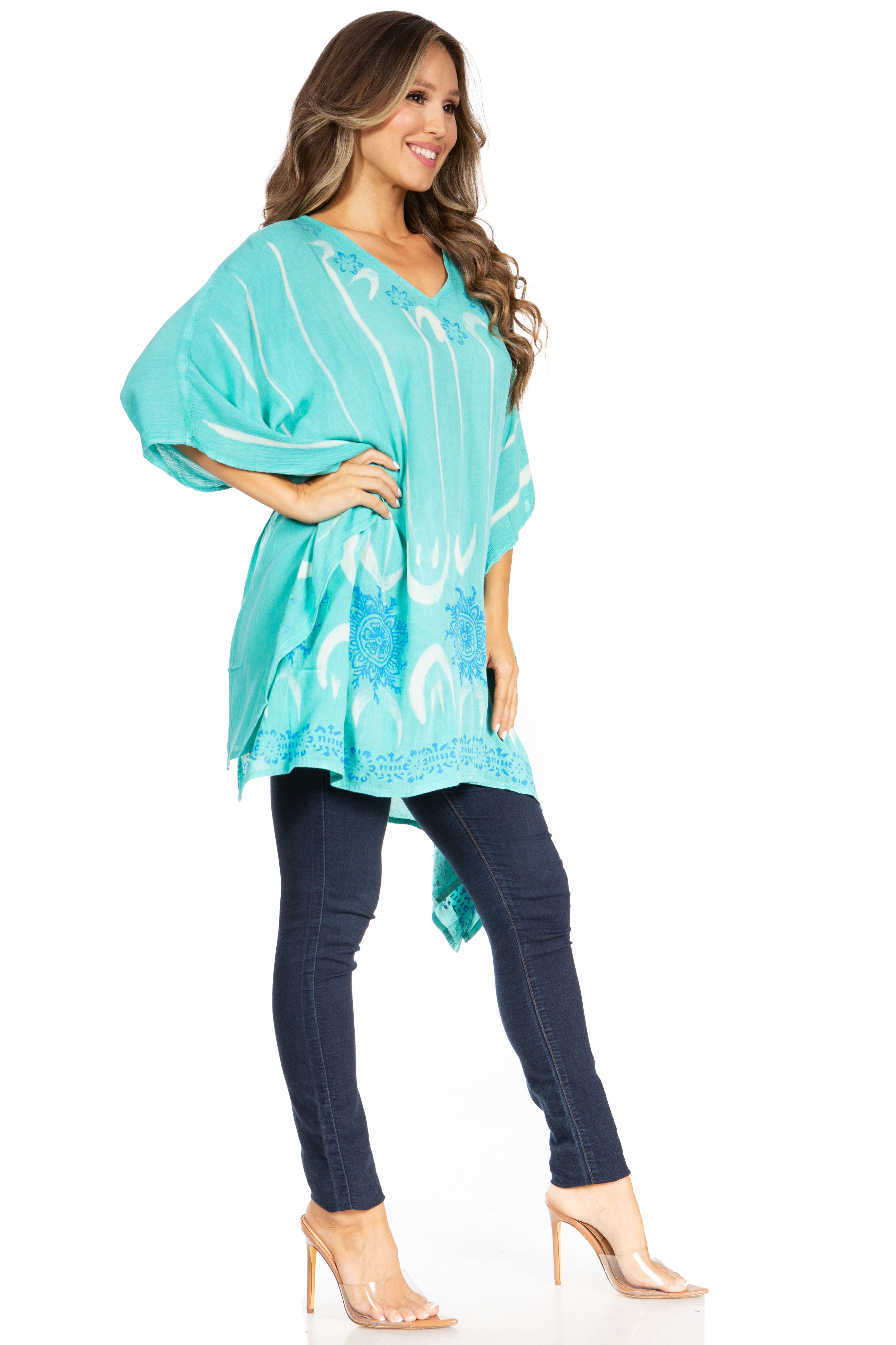 Woman wearing a turquoise patterned top and dark jeans on a white background