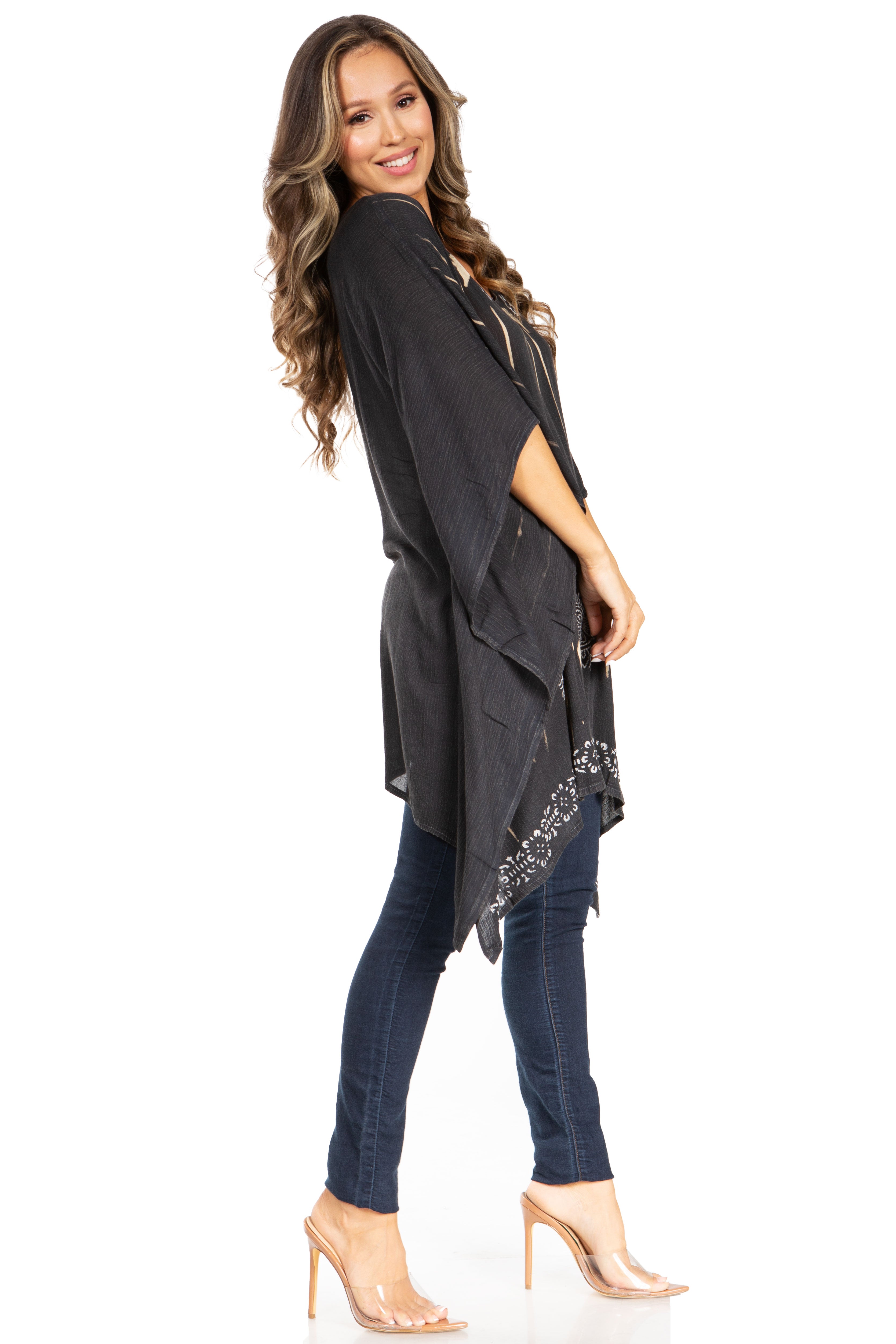 Woman wearing a black poncho with floral embellishments over a dark outfit on a white background