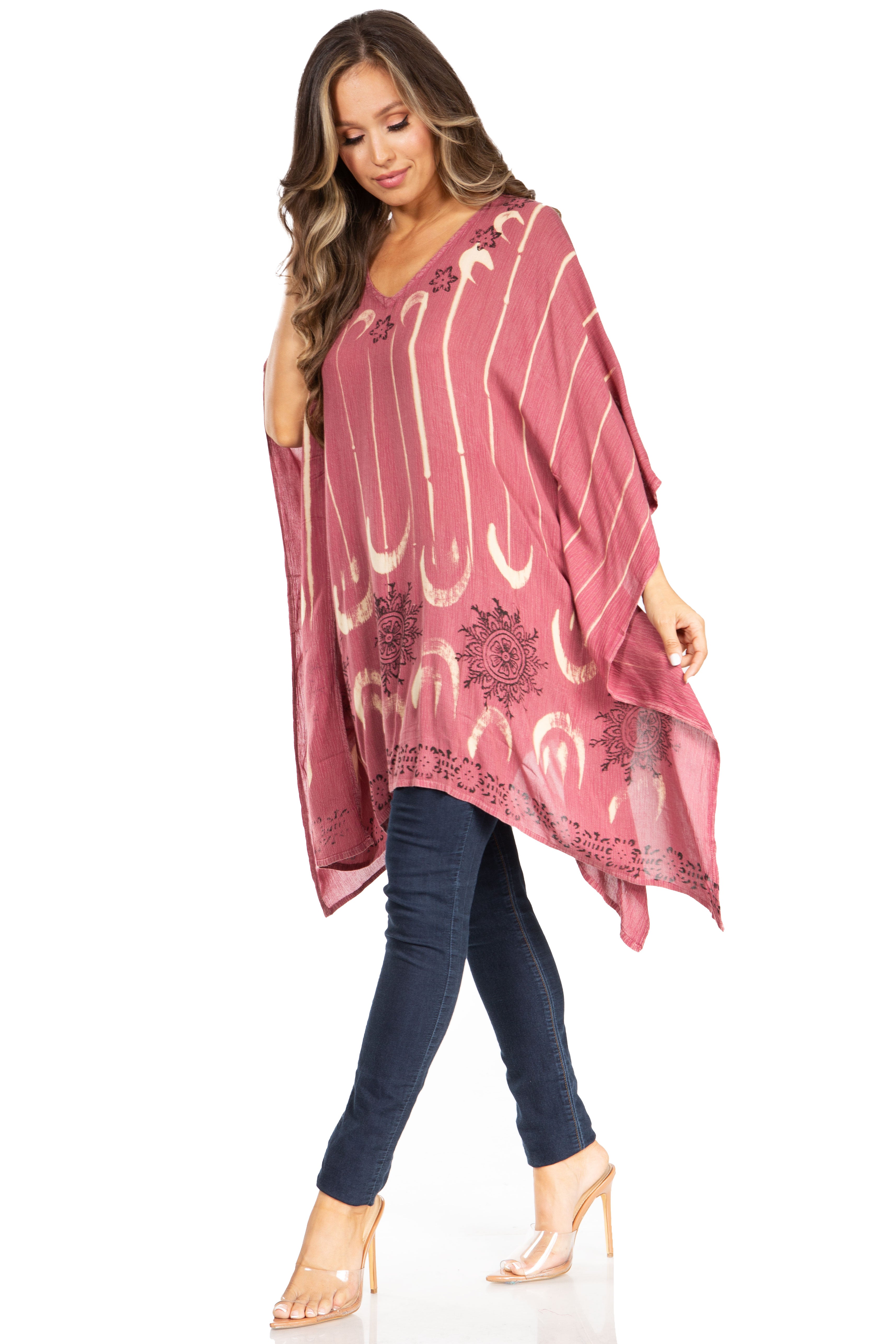 Woman wearing a pink patterned dress over a blue top and jeans on a white background