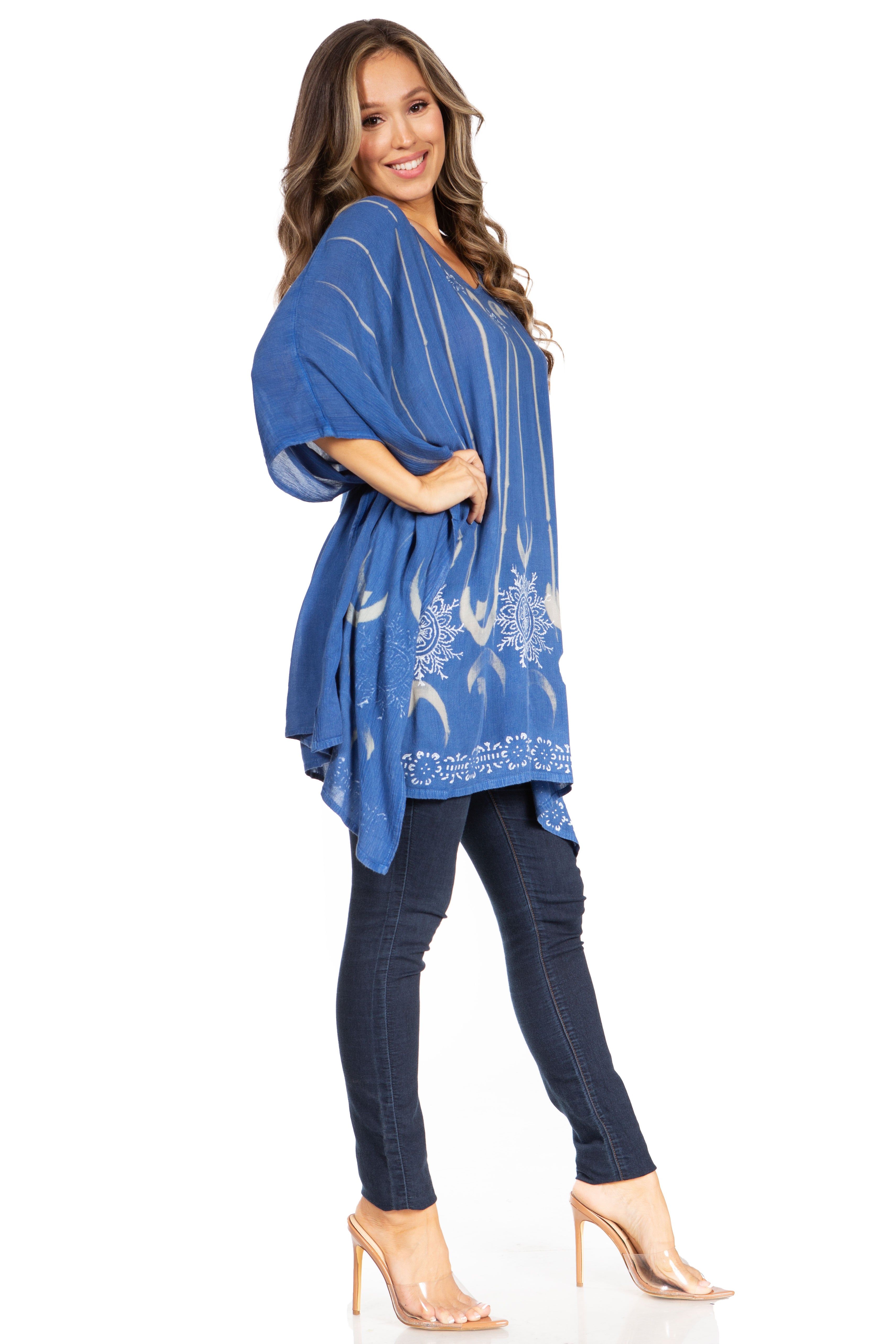 Woman wearing a blue patterned dress over dark jeans on a white background