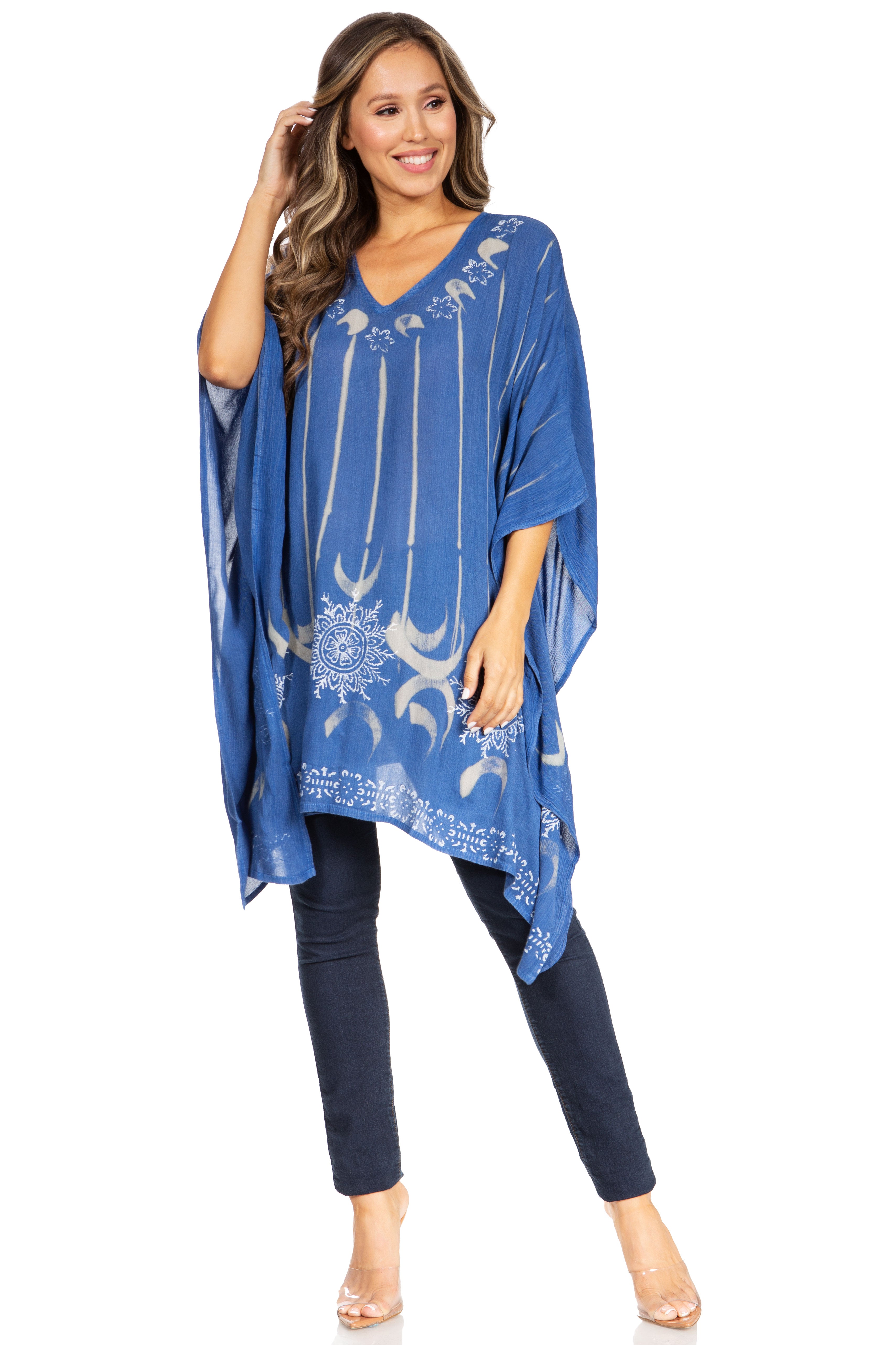 Woman wearing a blue patterned poncho over dark pants on a white background
