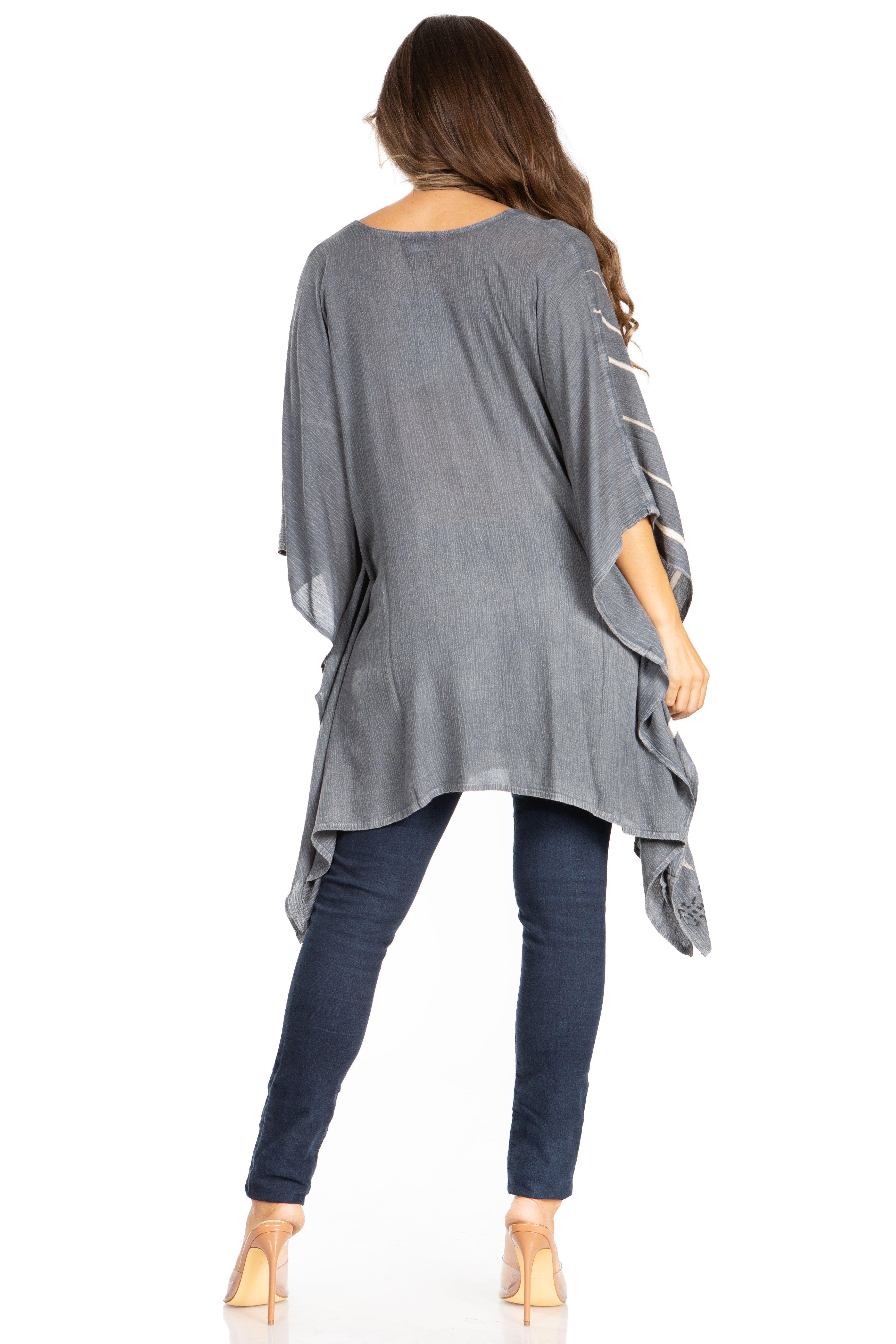Woman wearing a gray poncho over a blue outfit on a white background