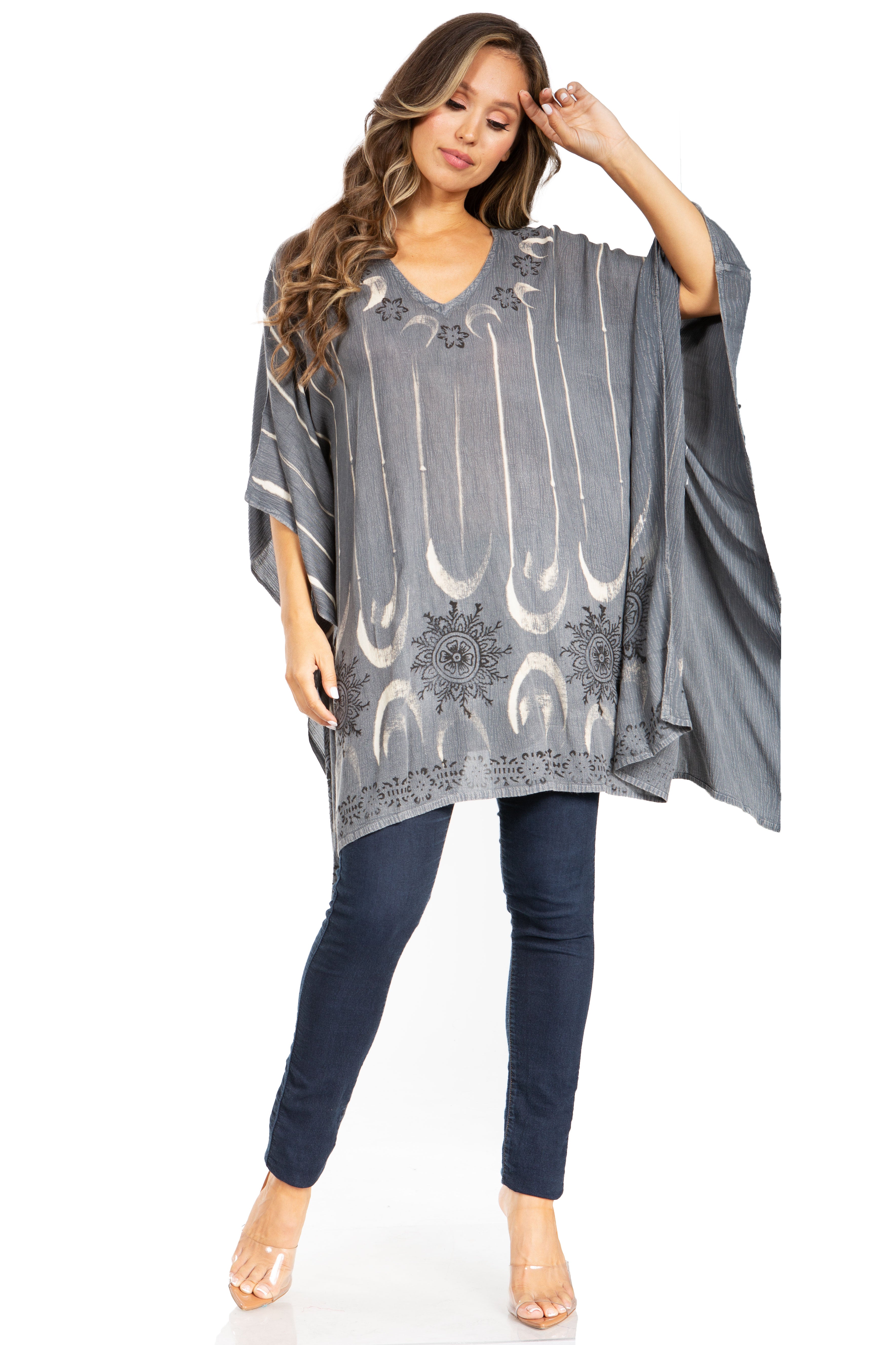 Woman wearing a gray patterned poncho over a navy outfit on a white background
