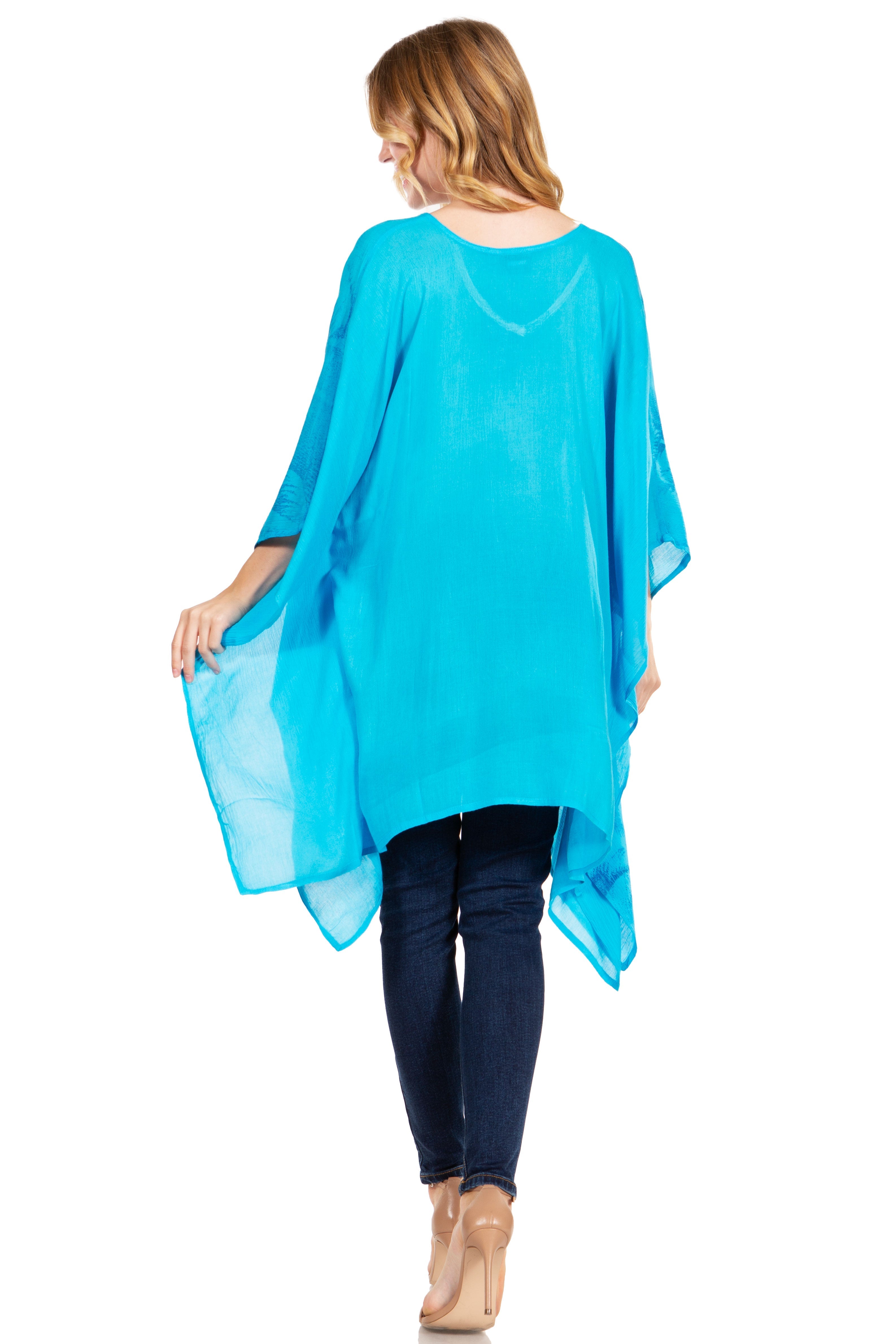 Woman wearing a turquoise sheer top with dark jeans on a white background