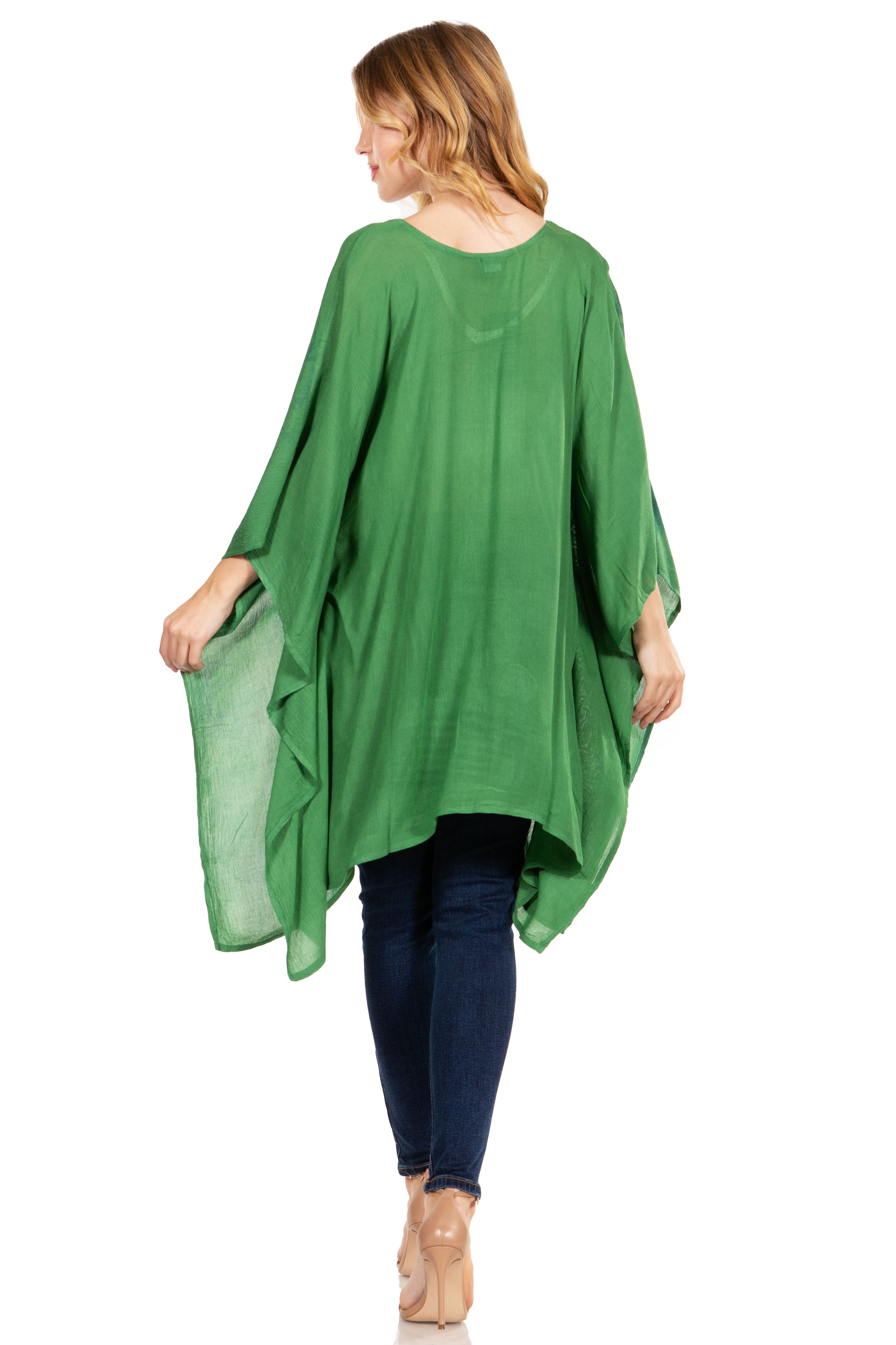 Woman wearing a green poncho over a blue outfit on a white background