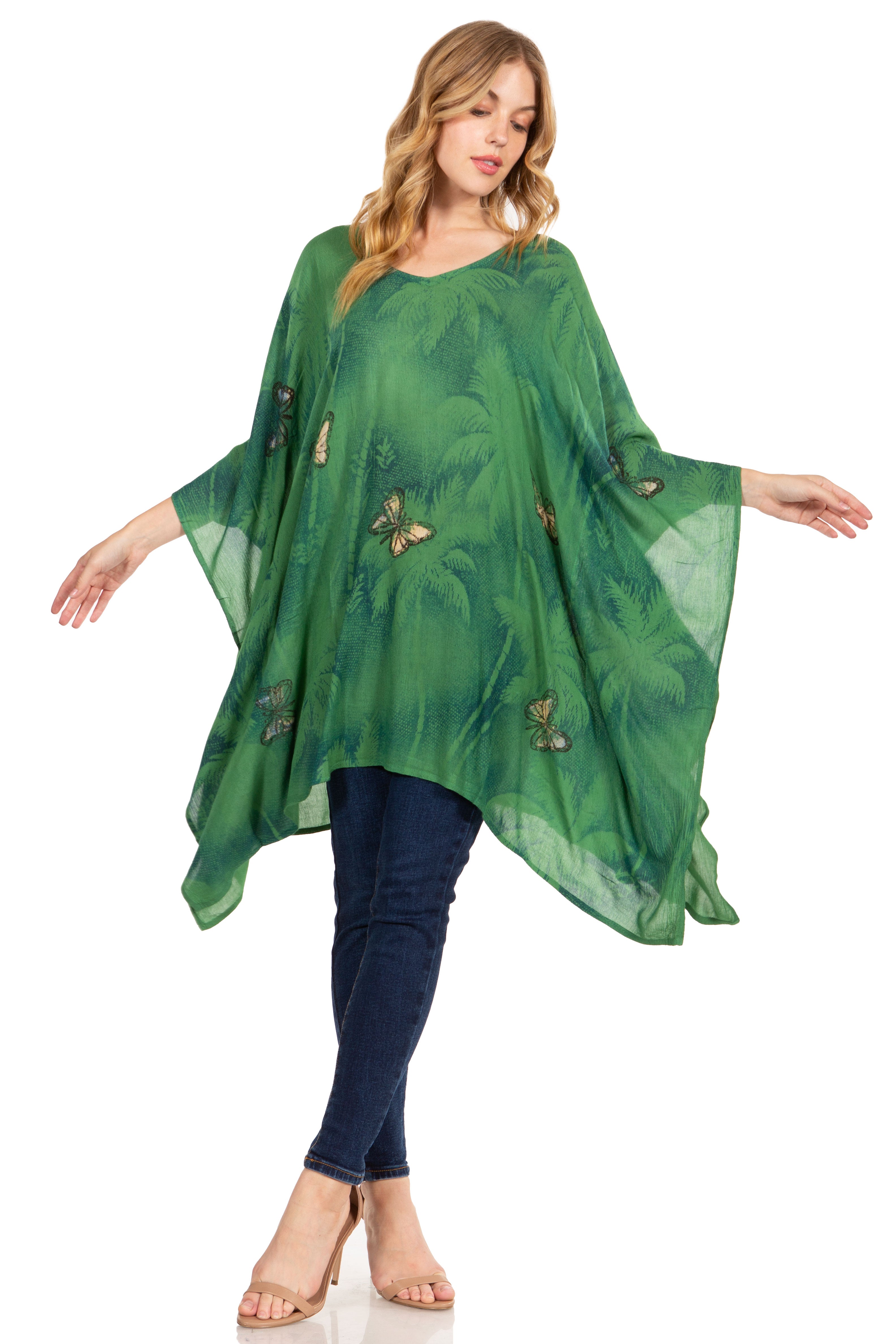 Woman wearing a green floral dress over blue jeans on a white background