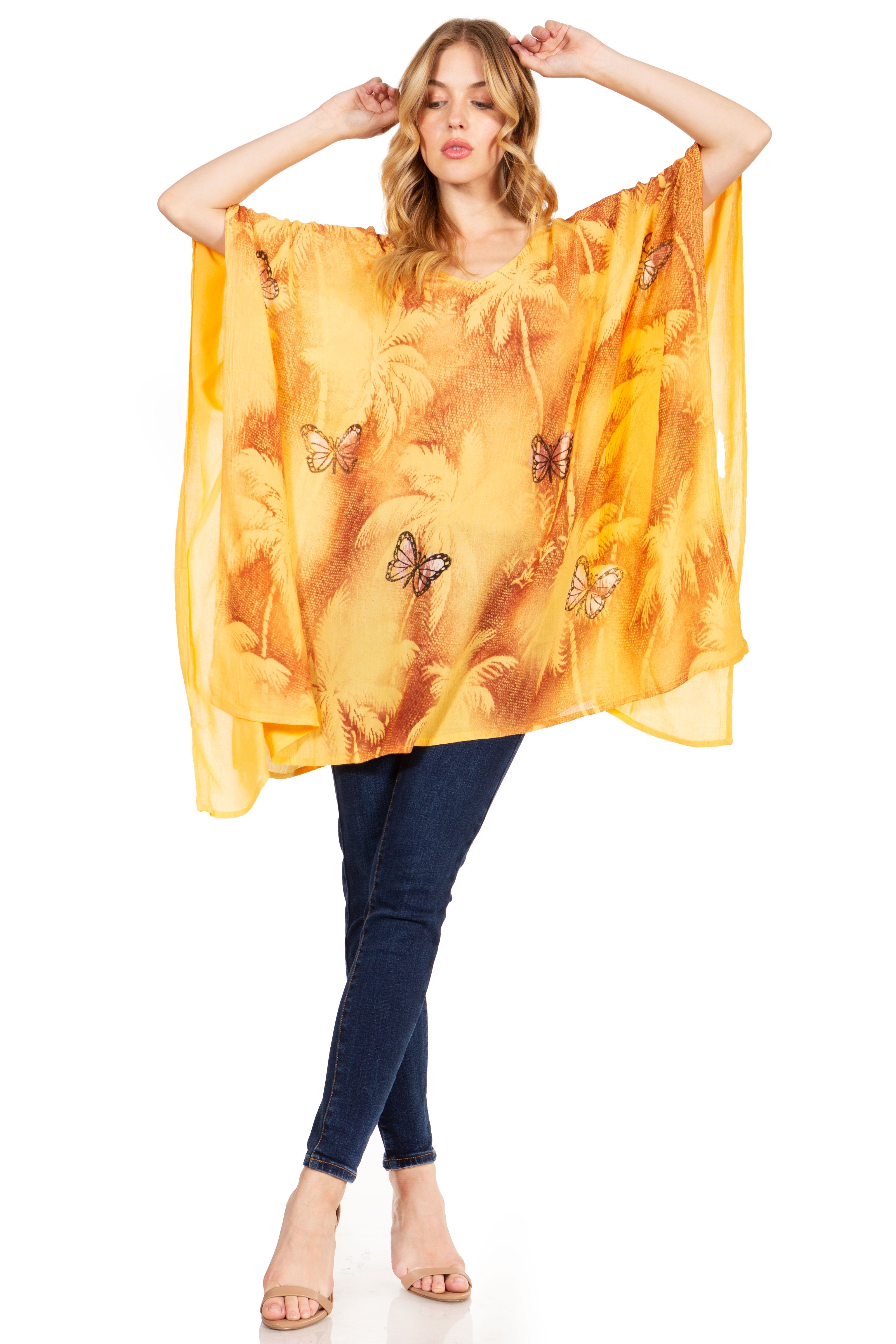 Woman wearing a yellow butterfly-patterned kaftan over dark jeans on a white background