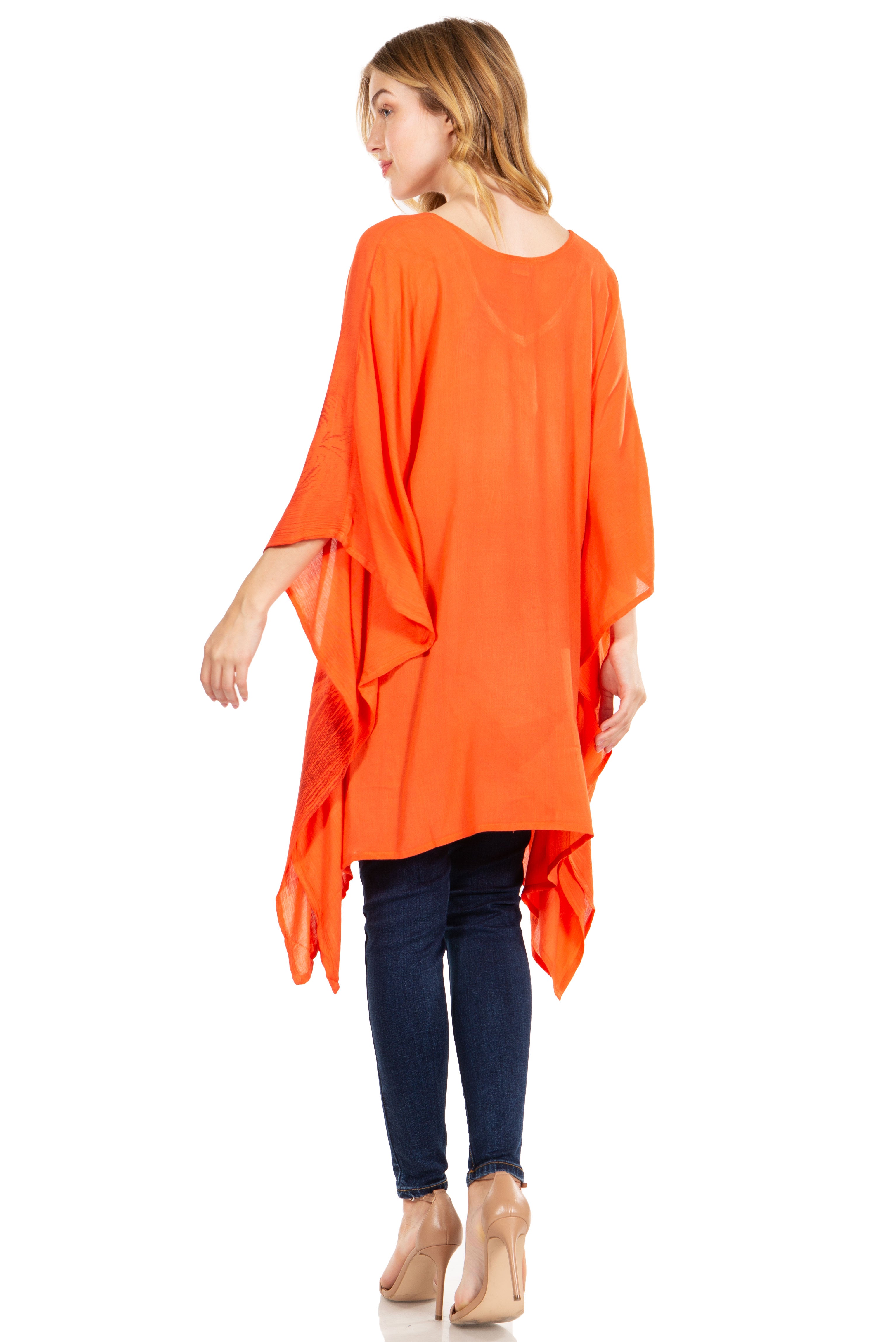 Woman wearing an orange flowing top and blue jeans on a white background