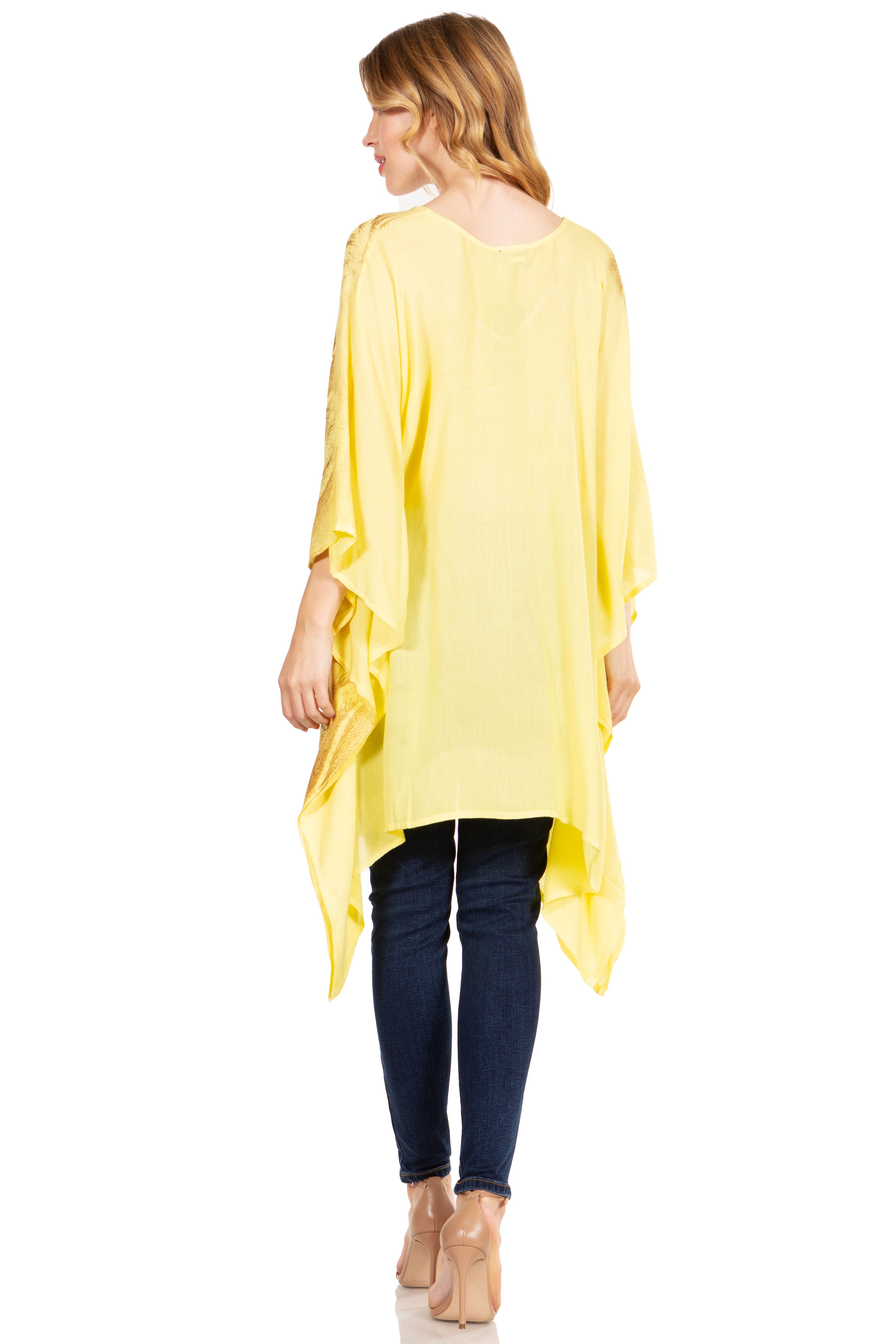 Woman wearing a yellow oversized top and dark jeans on a white background