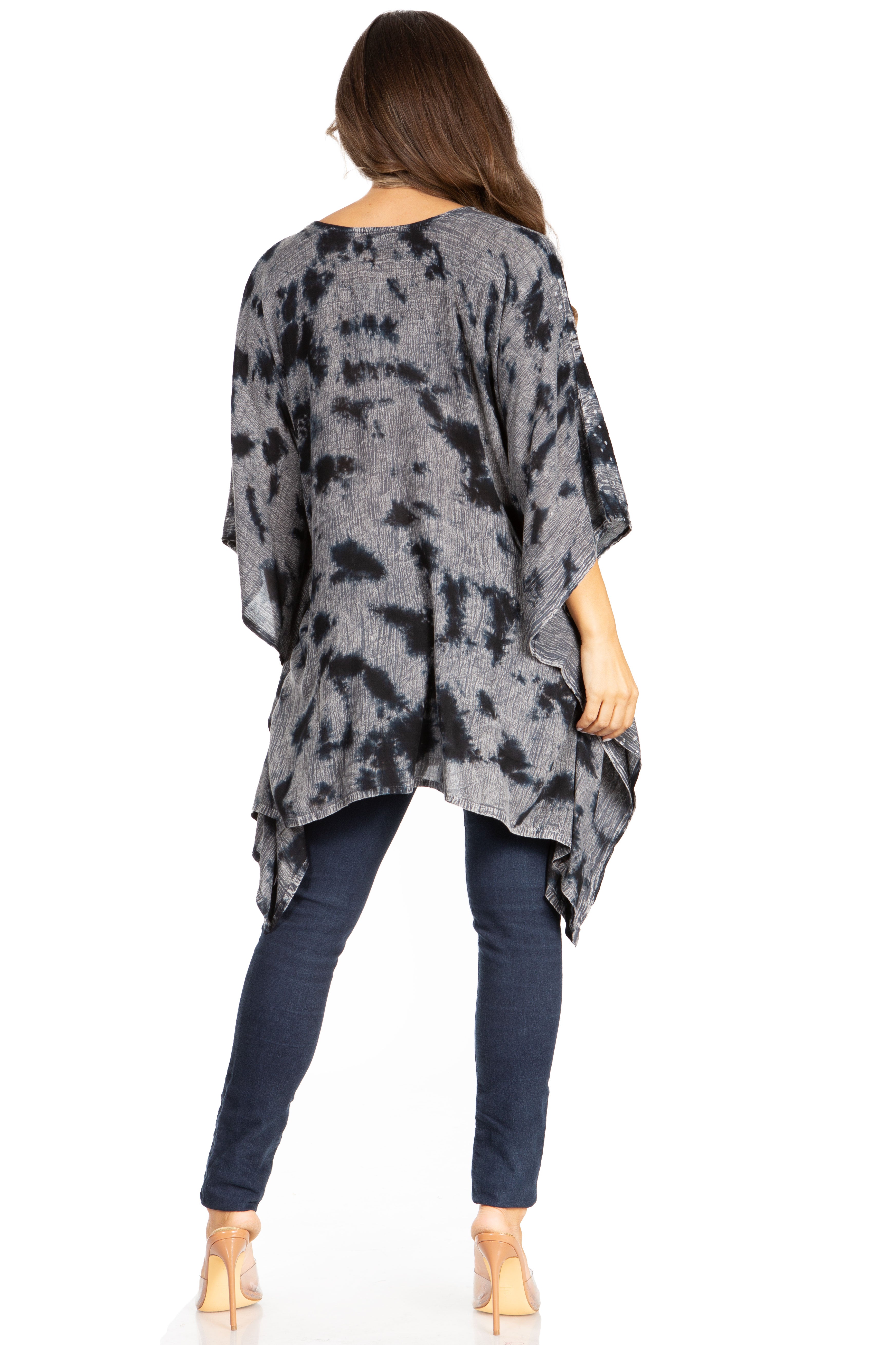 Woman wearing a tie-dye poncho and dark jeans on a white background