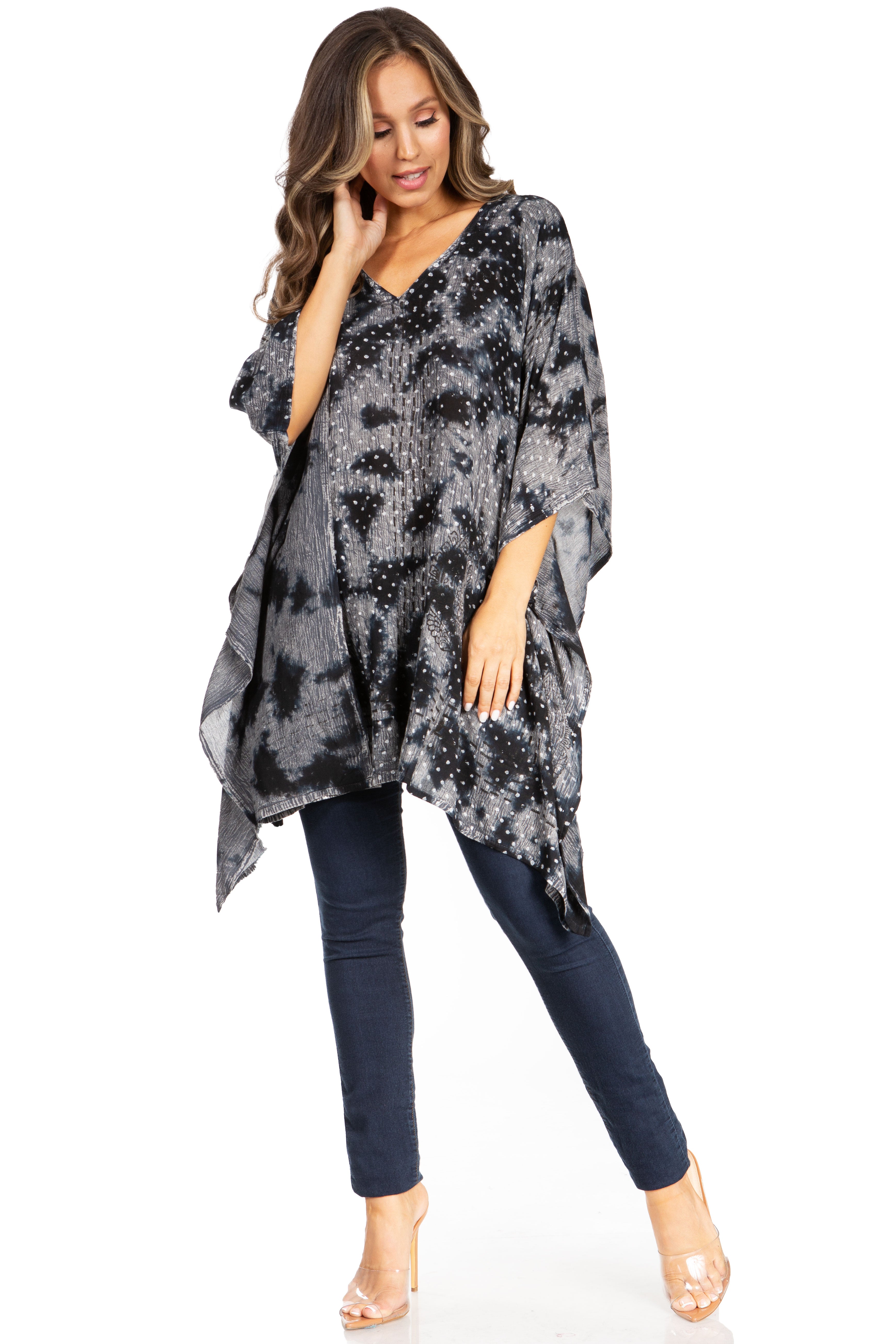 Woman wearing a black and gray patterned poncho over a dark outfit on a white background