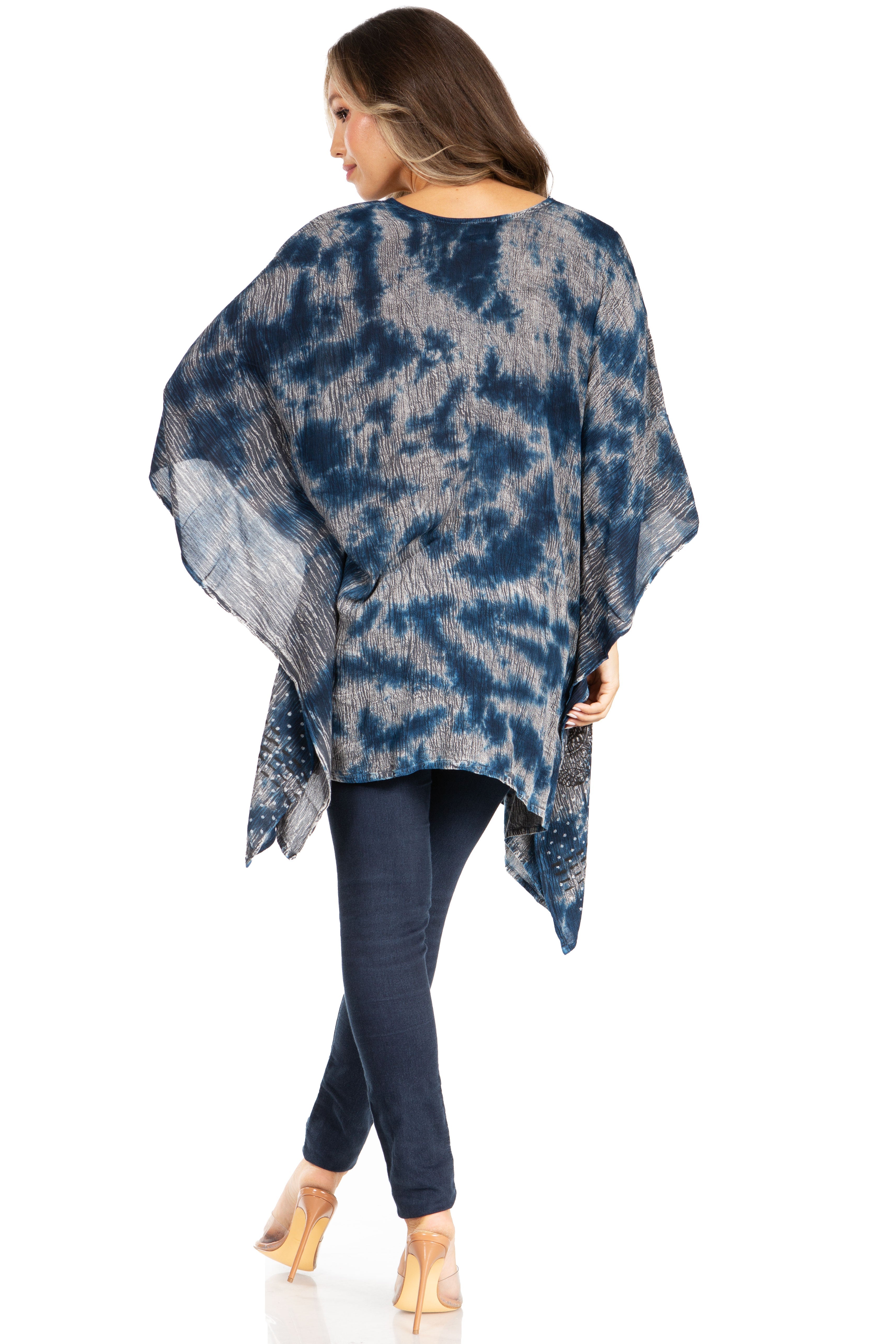 Woman wearing a blue tie-dye poncho and dark pants on a white background