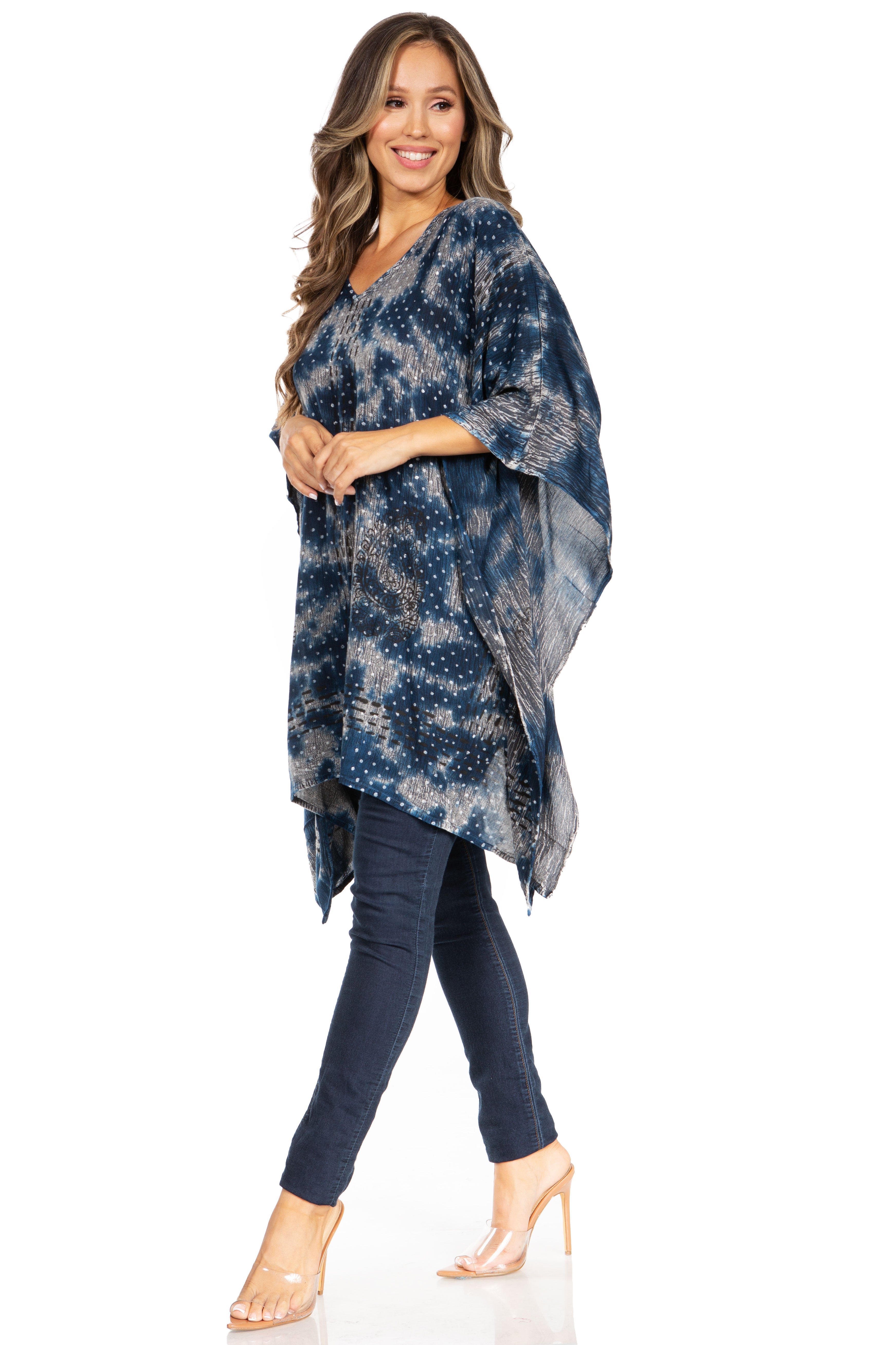Woman wearing a blue patterned poncho over a dark outfit on a white background