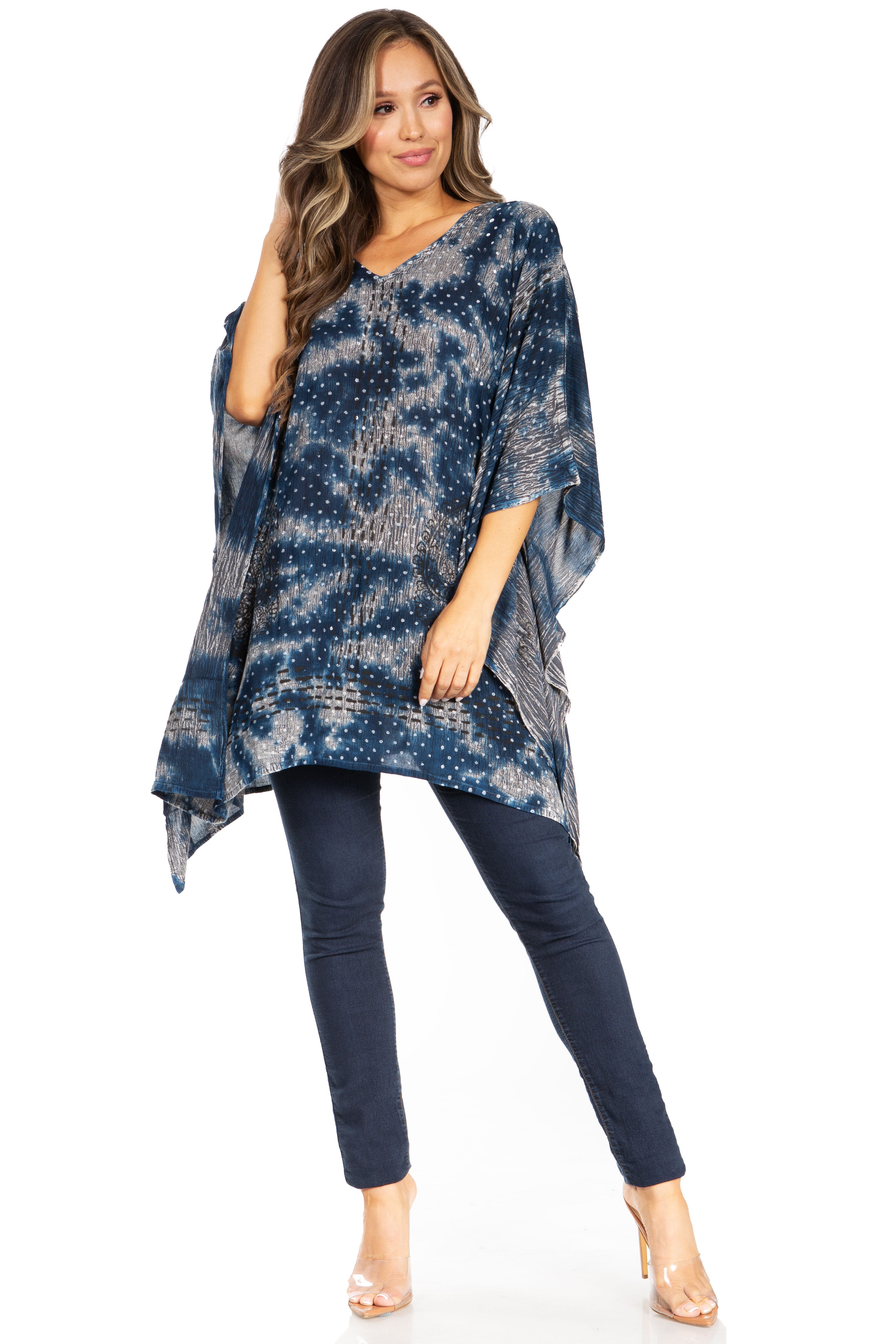 Woman wearing a blue tie-dye poncho and dark jeans on a white background